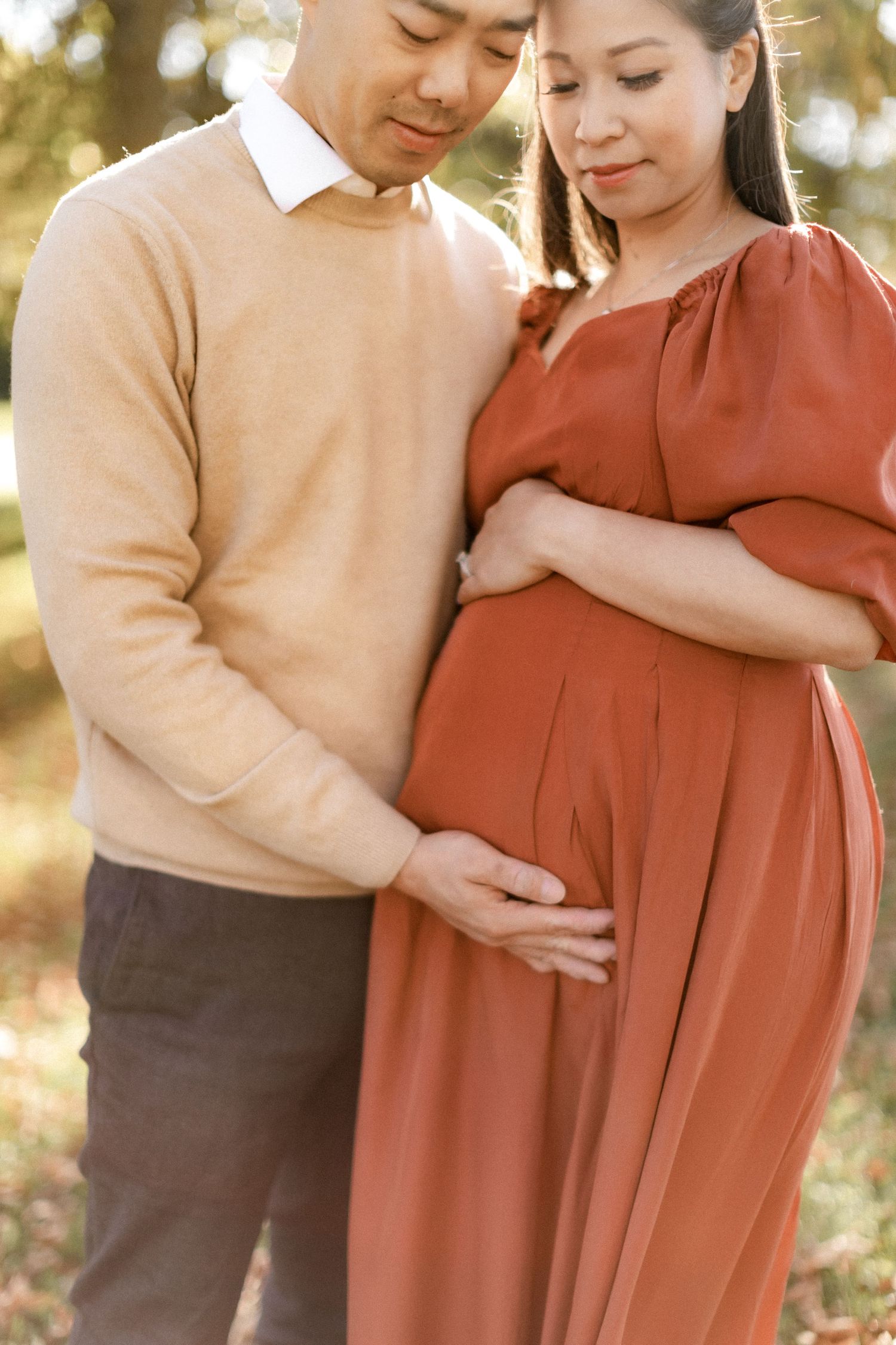 An intimate maternity portrait showing a couple tenderly embracing in warm autumn lighting.