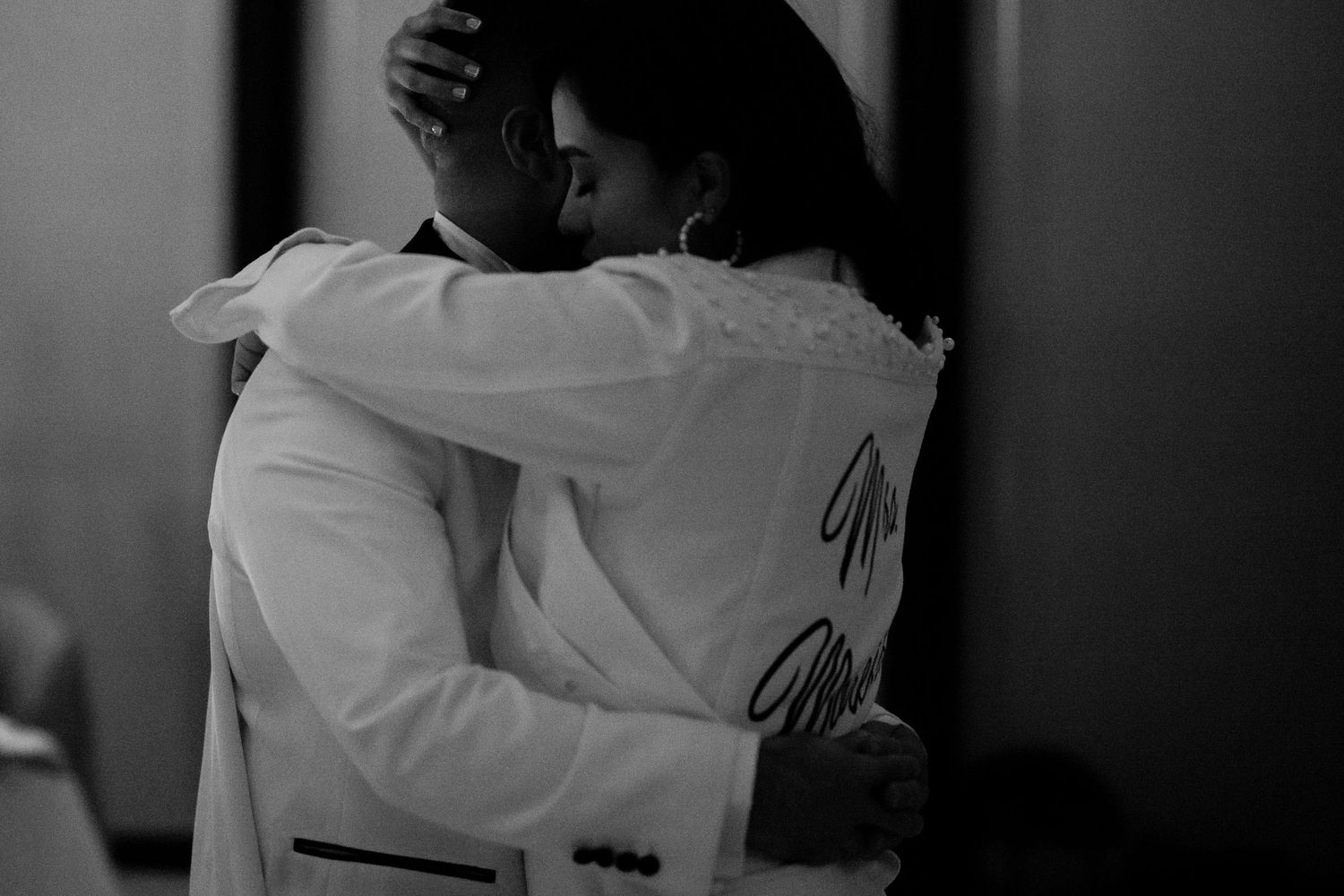 An intimate black and white moment of a couple embracing during their dance.