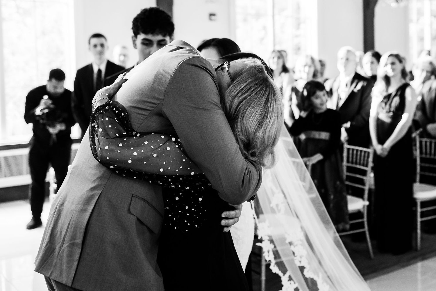 Black and white photo of embracing moments during wedding ceremony in elegant venue.