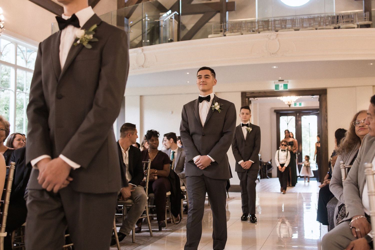 Formal wedding ceremony in a modern chapel with white walls and exposed wooden beams.