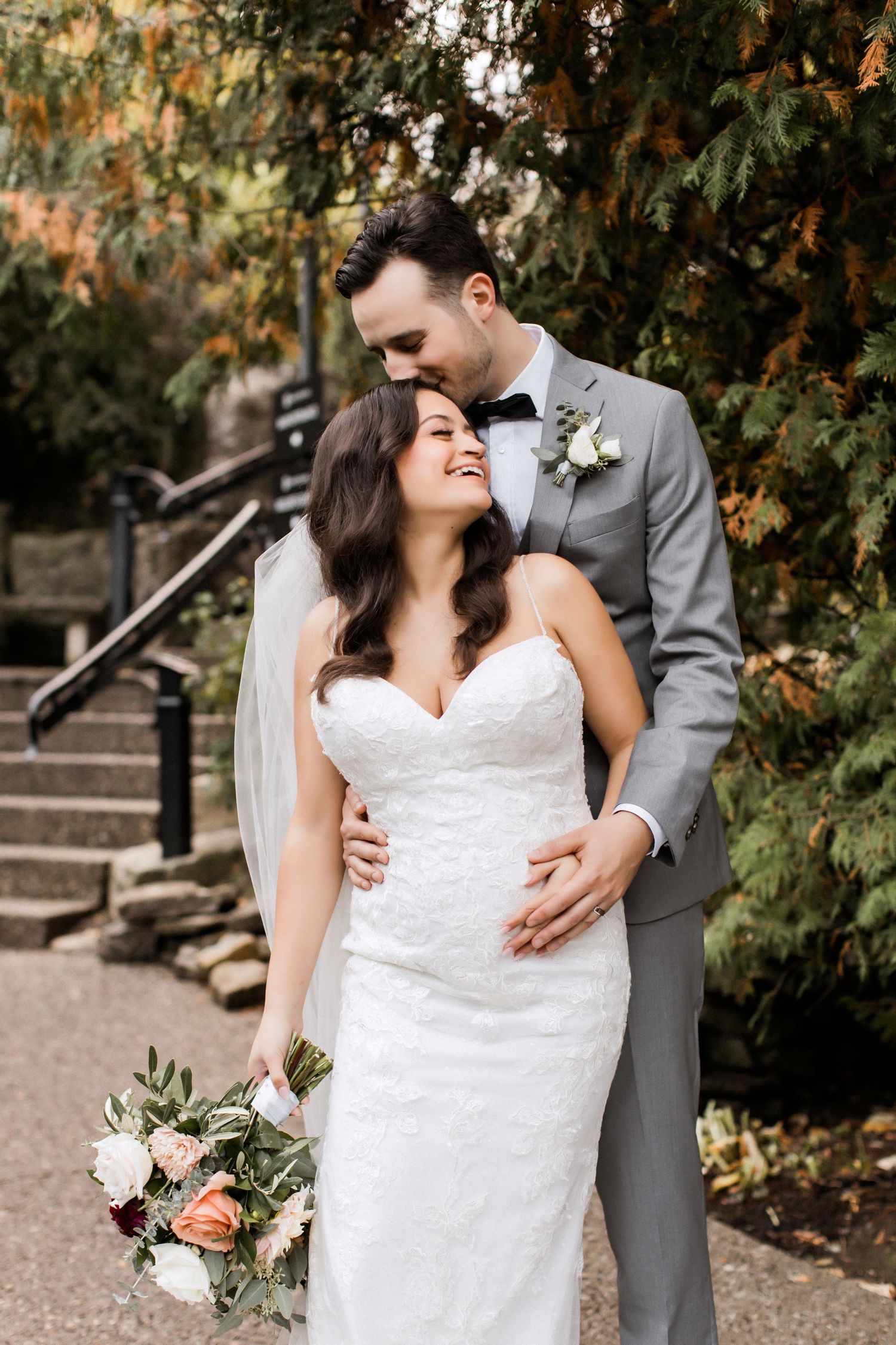 Candid moment between newlyweds surrounded by autumn foliage and stone steps.