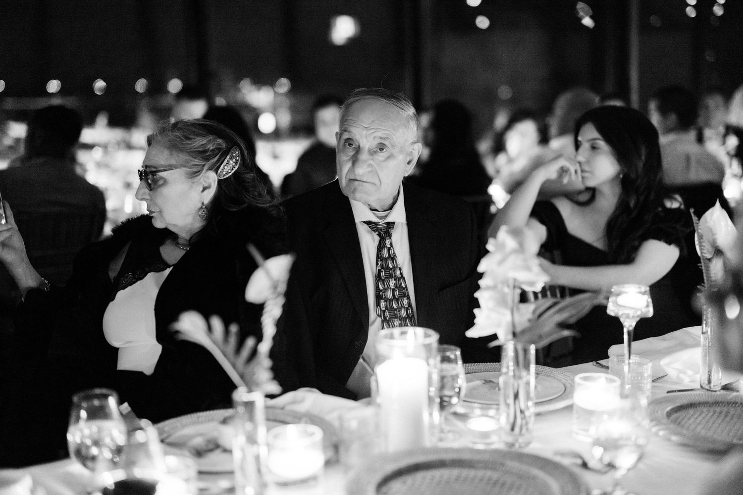 Guests enjoy conversation at an elegant candlelit wedding reception dinner.