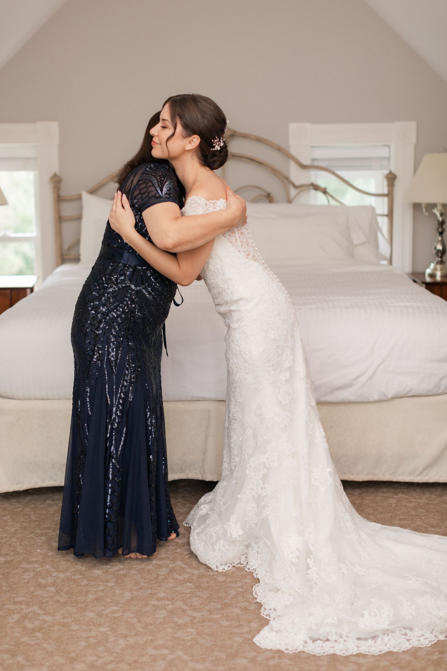 A touching embrace between two people in formal attire in an elegant bedroom setting.