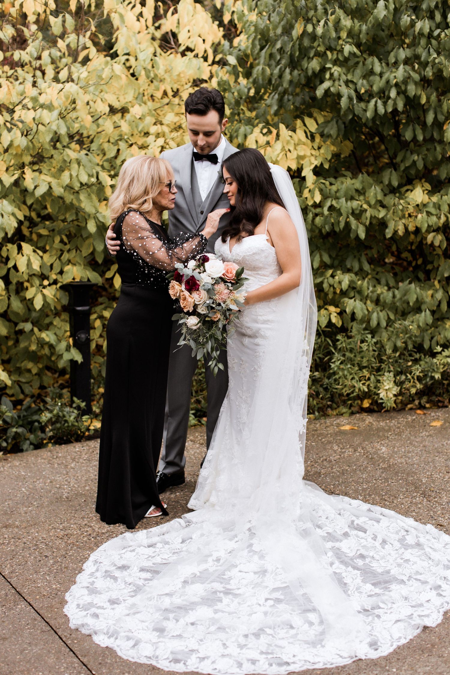 Outdoor wedding moment with beautiful floral bouquet against autumn foliage backdrop.
