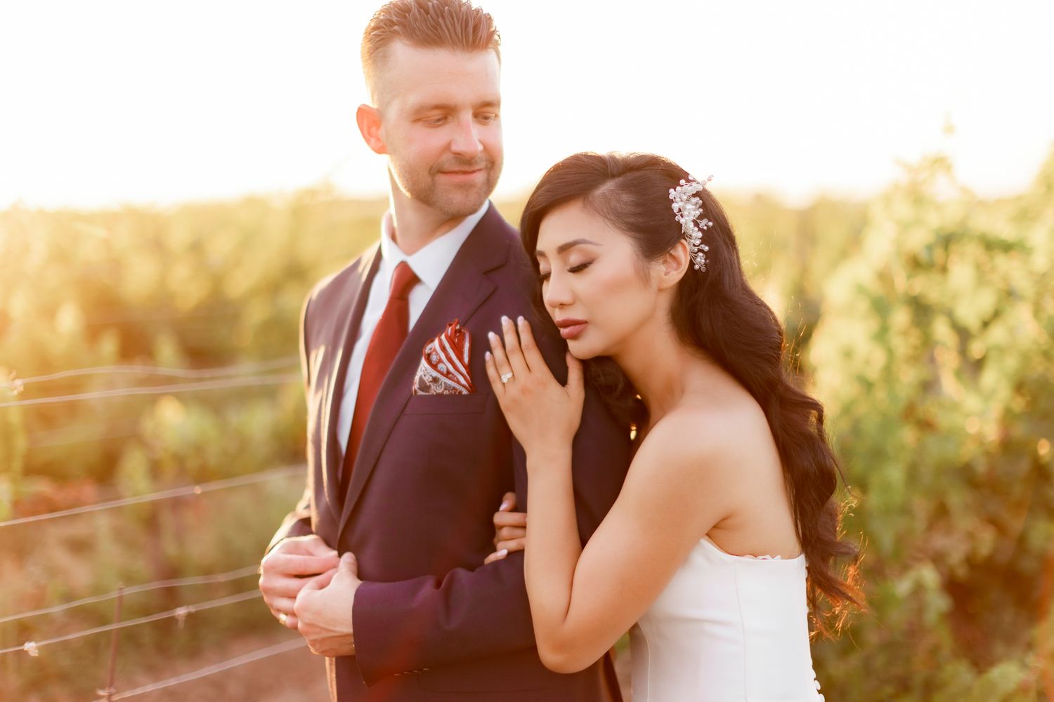 A romantic sunset photo of a couple at a vineyard in elegant wedding attire.