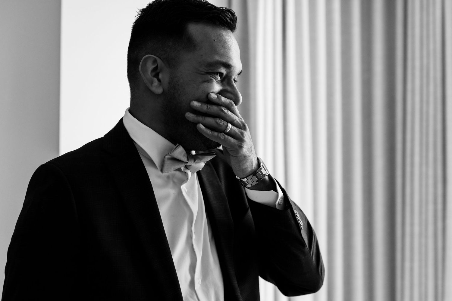 A candid black and white portrait showing an emotional moment in formal attire.