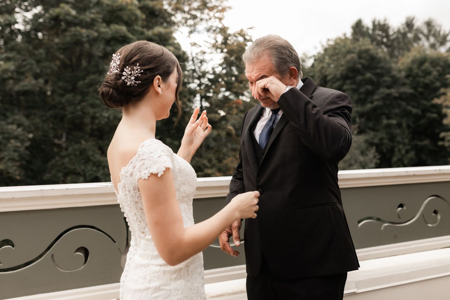 Emotional first look moment between bride and father on outdoor balcony during wedding day.