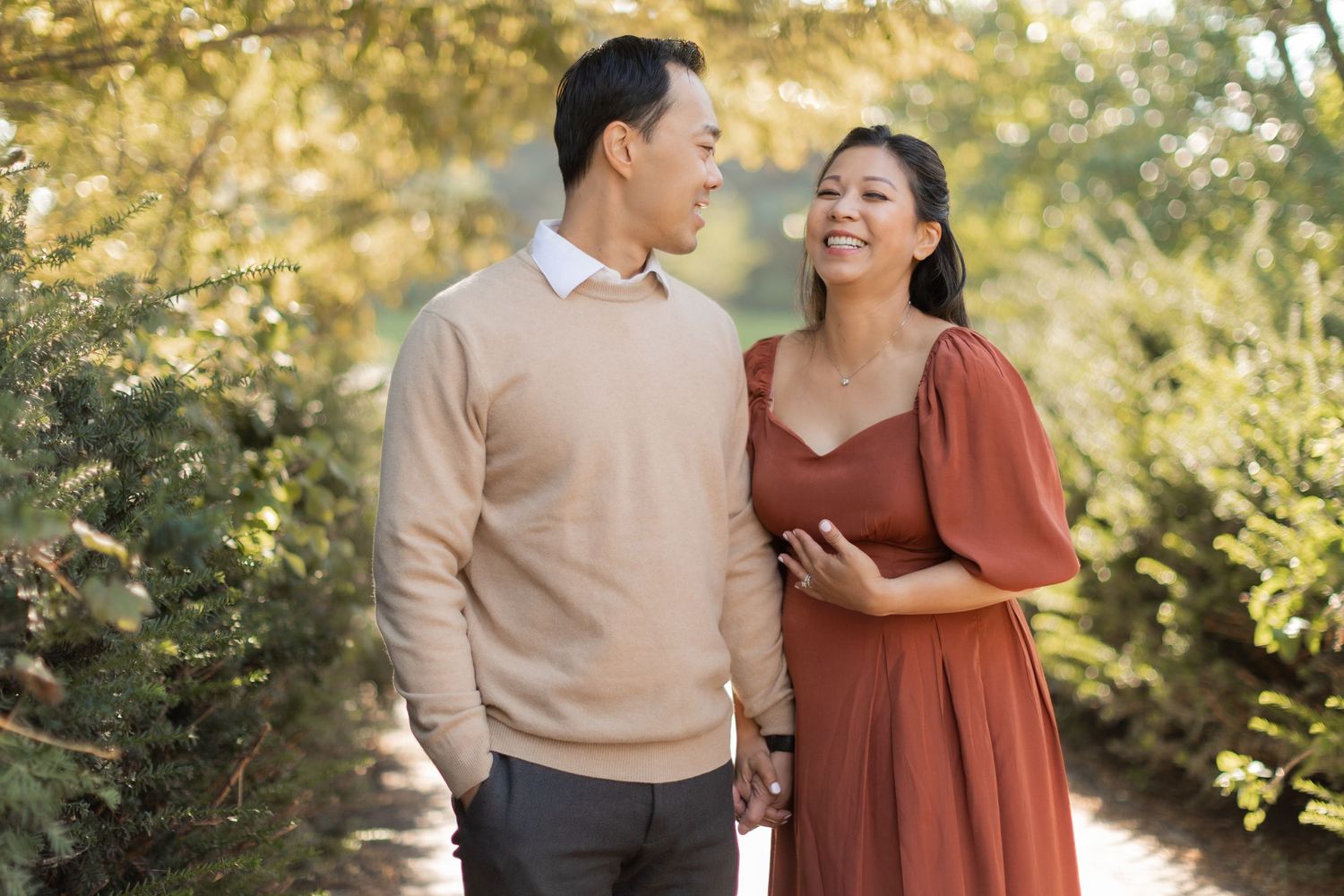 Happy couple in coordinated outfits sharing loving moment during outdoor pregnancy photoshoot.