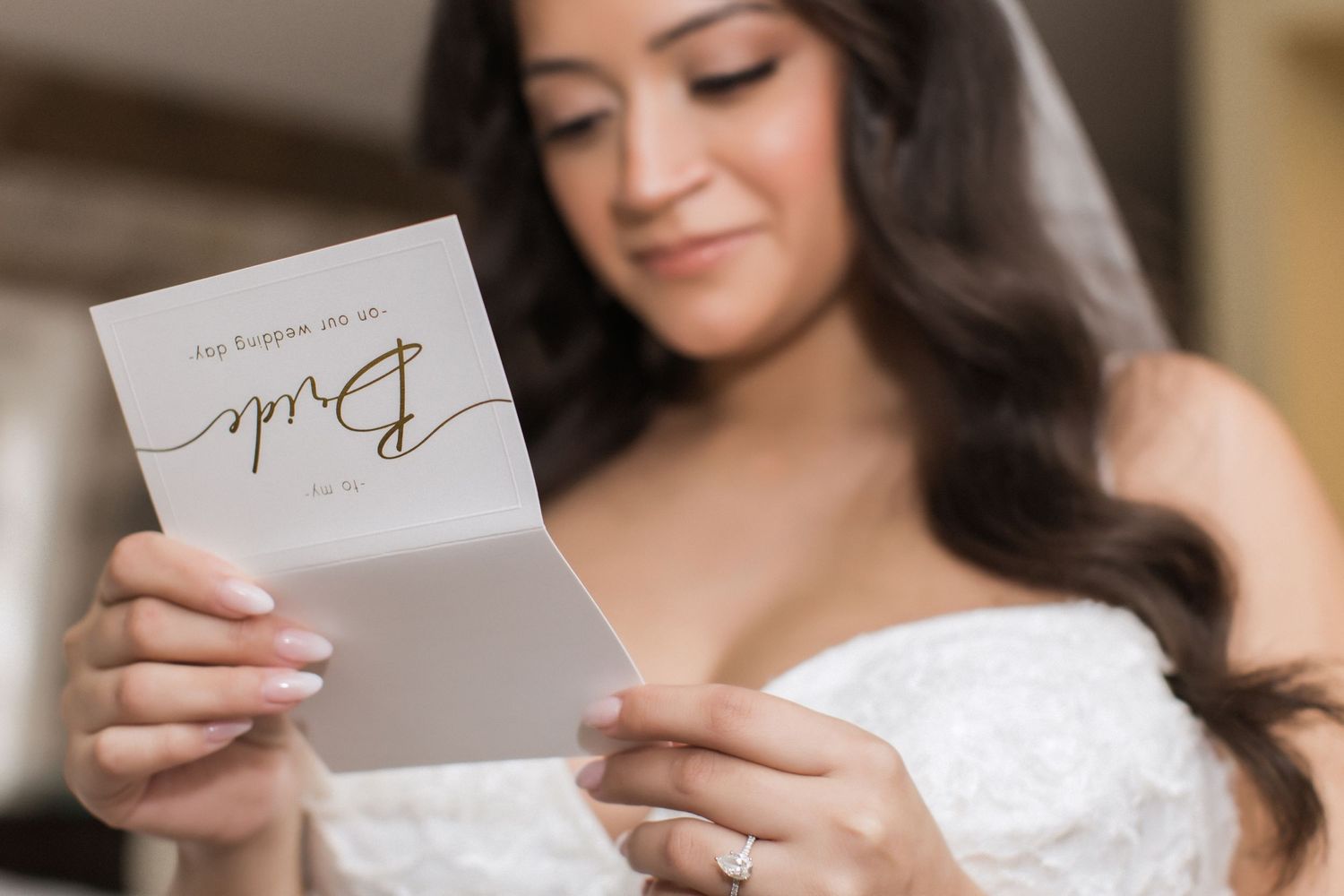 Emotional bride smiling while reading a handwritten note in her wedding dress.