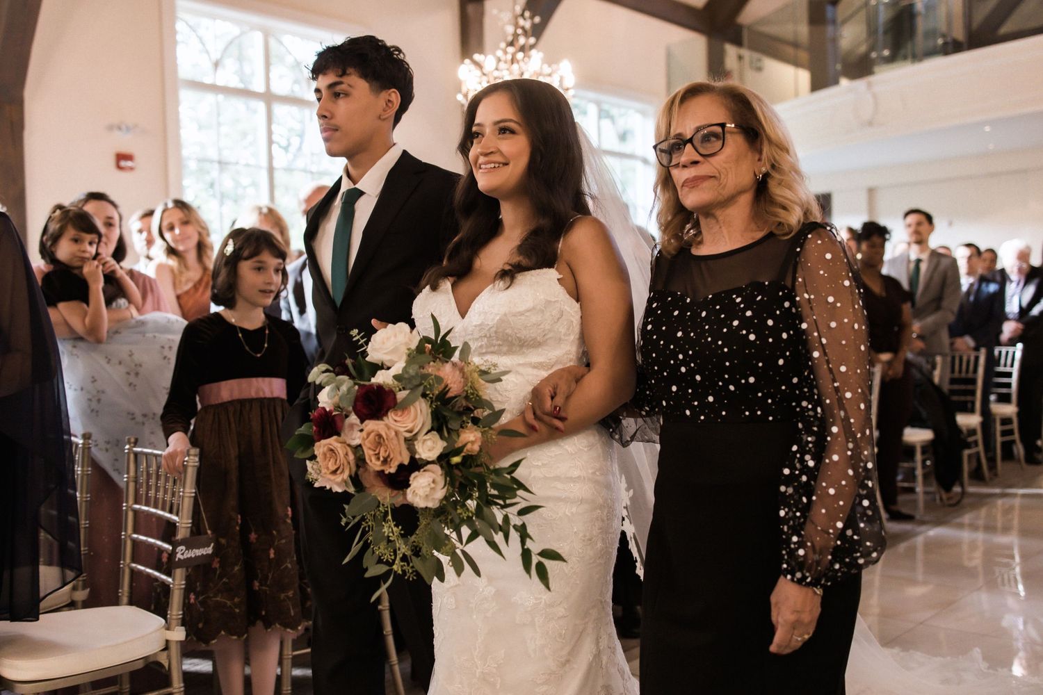 Wedding processional in an elegant chapel with warm lighting and exposed wooden beams.