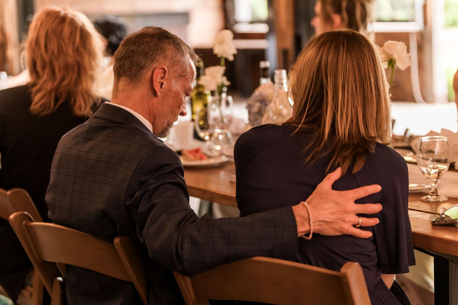 Guests engaging in lively conversation at a dimly lit restaurant dinner table.