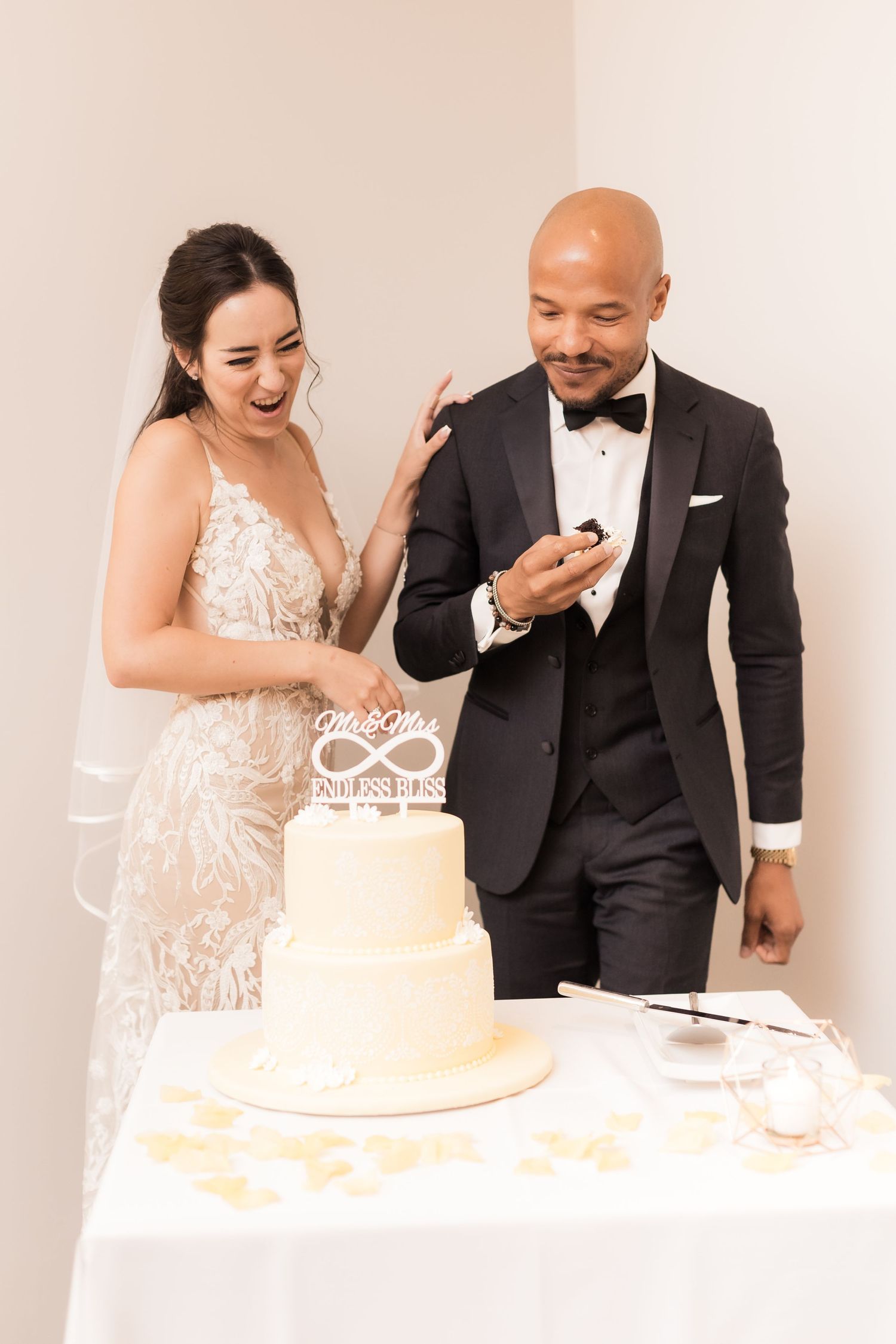 A couple joyfully tastes their wedding cake together during their reception celebration.
