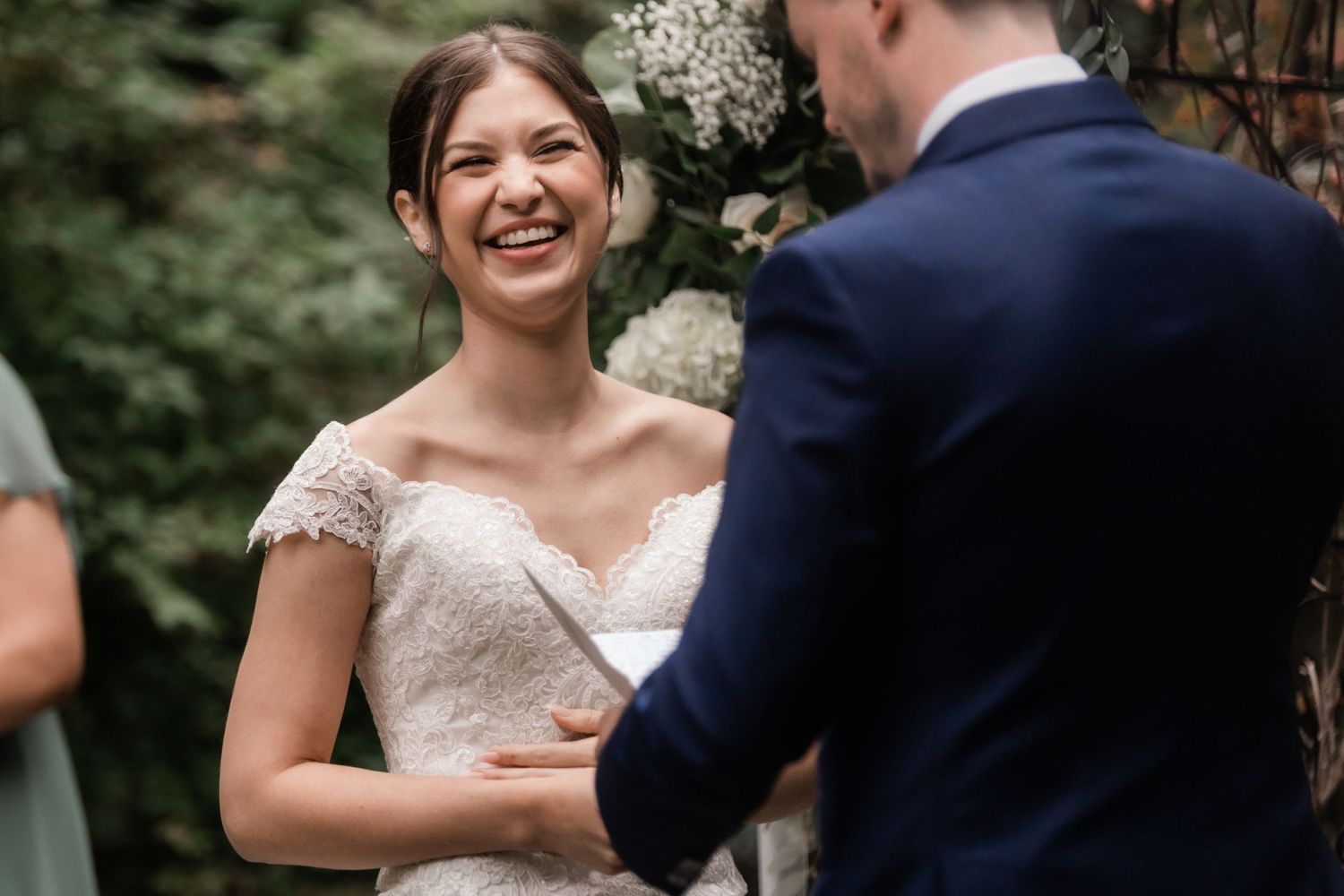 Joyful exchange of wedding vows in an intimate garden setting with greenery backdrop.