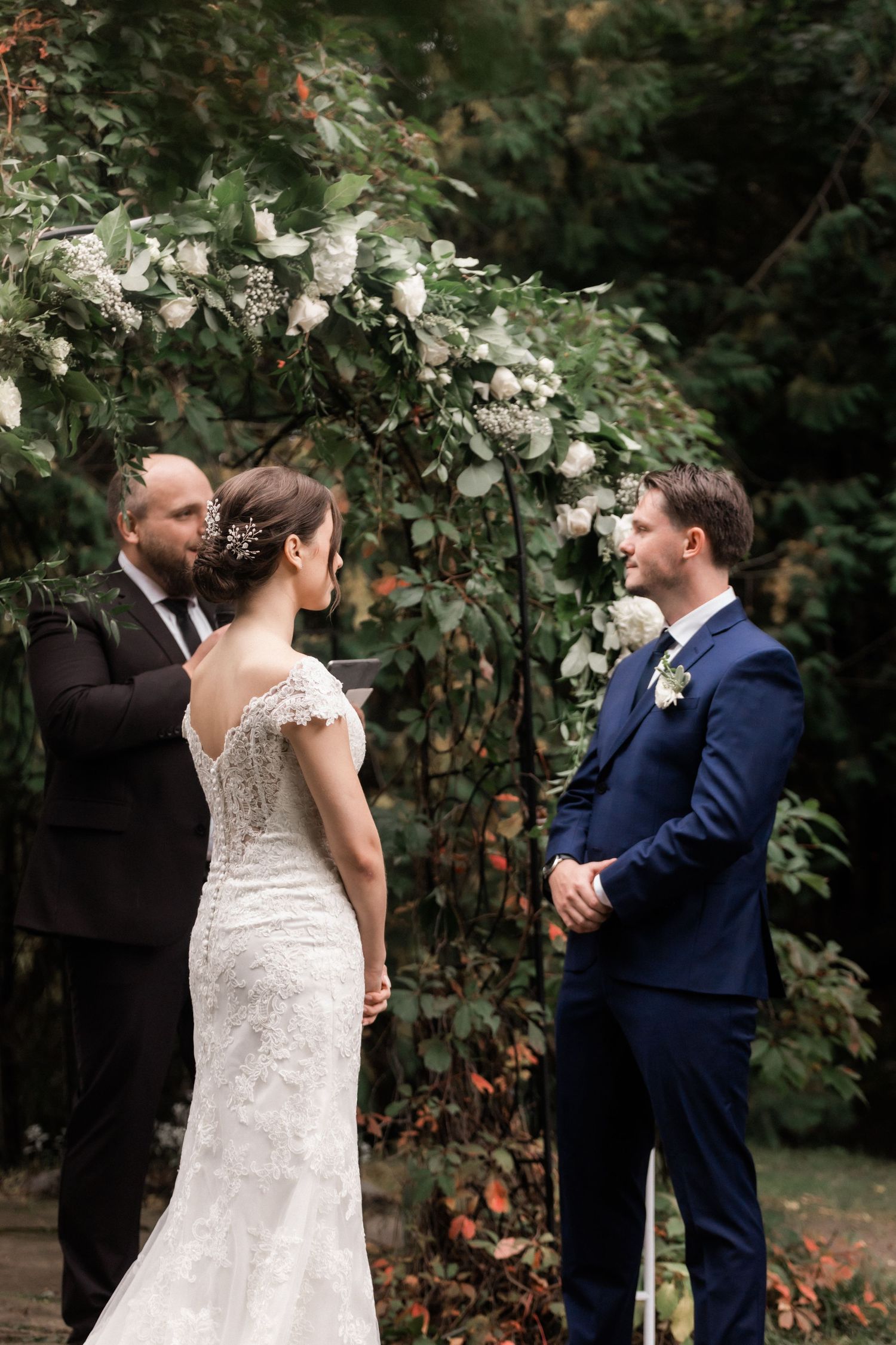 An intimate outdoor wedding ceremony surrounded by lush greenery and white flowers.