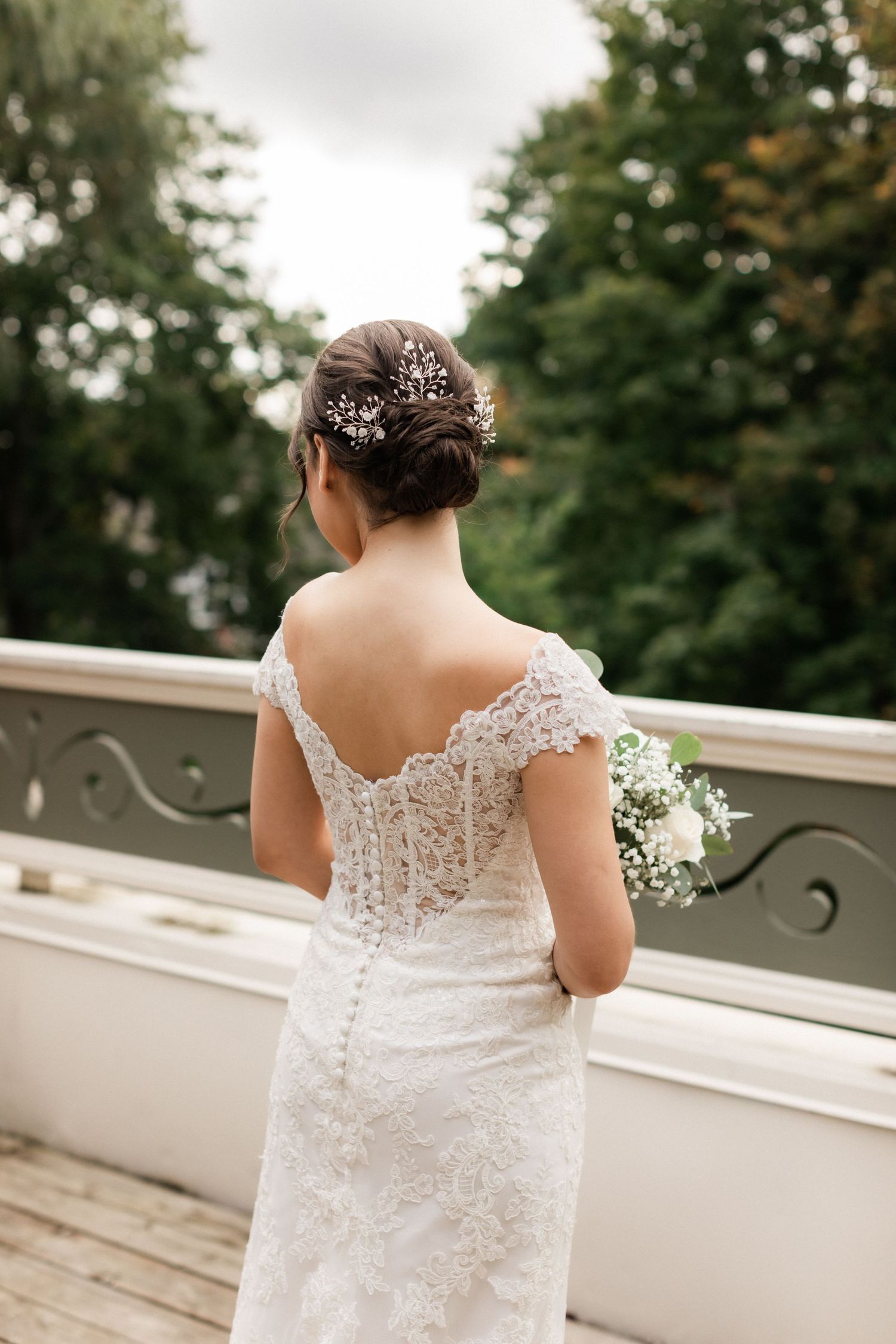 Back view of bride in lace dress with crystal hair accessories on outdoor balcony.