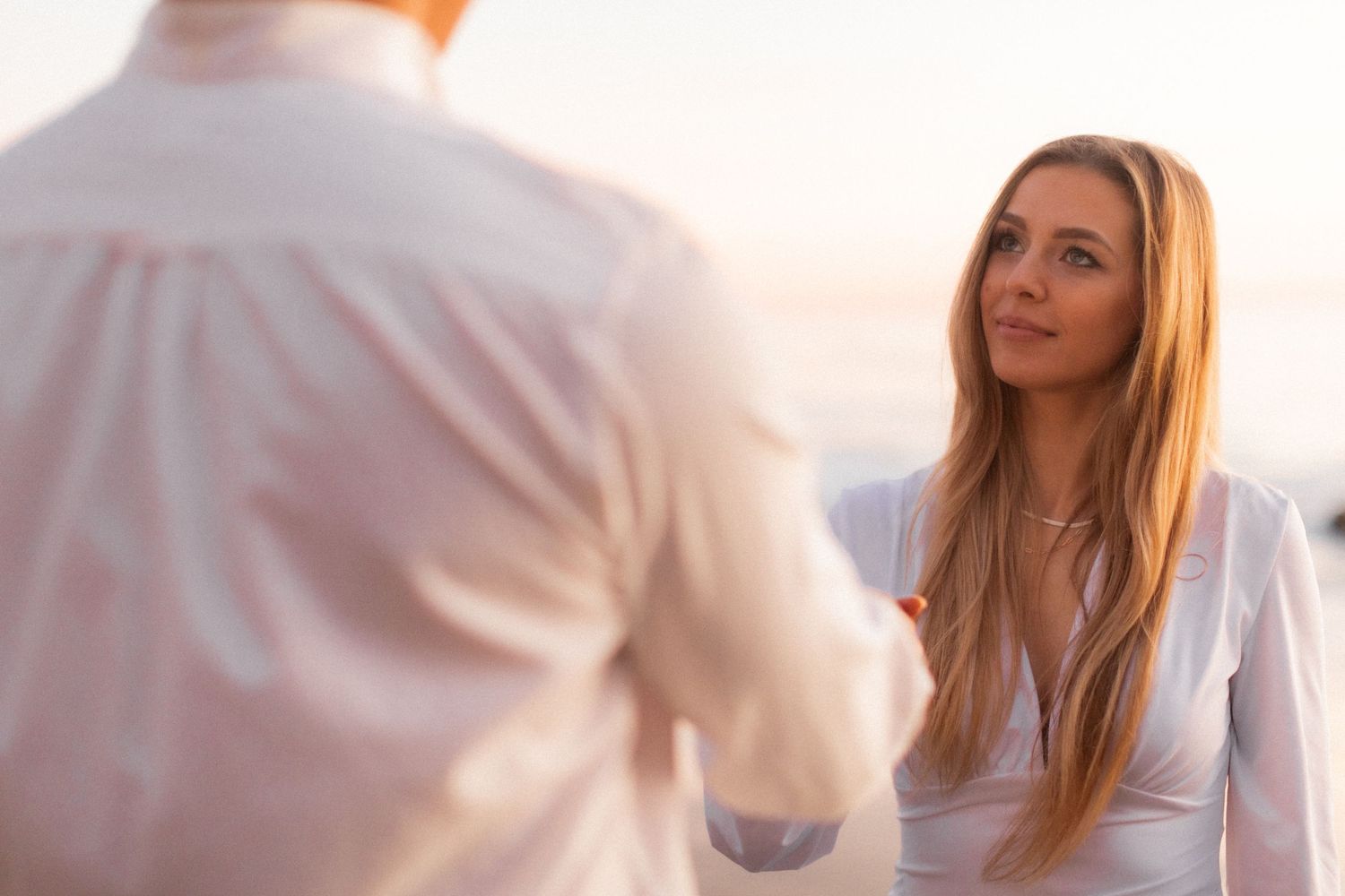Couple sharing romantic moment on beach during golden hour.