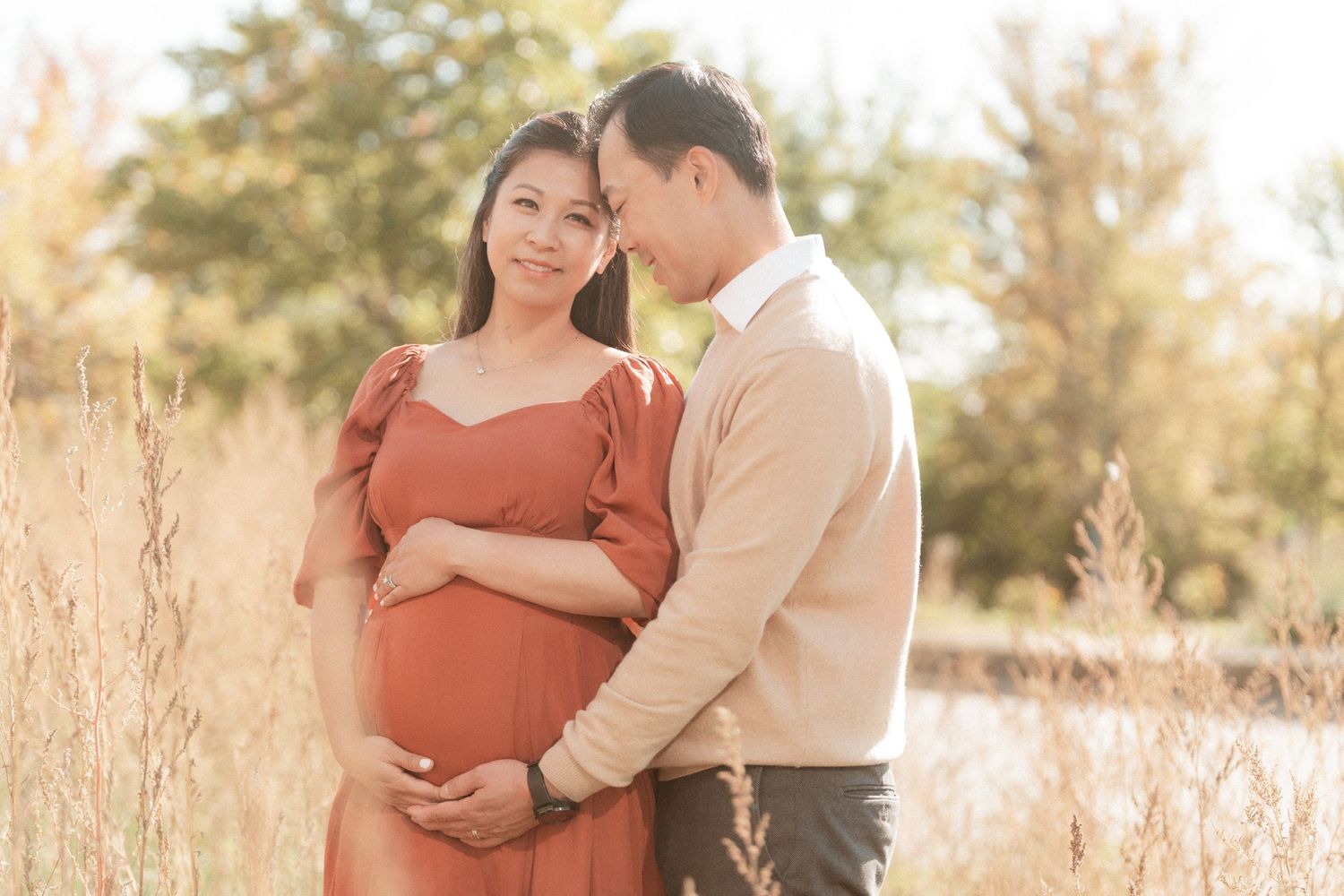 Gentle maternity photograph capturing couple's embrace in warm afternoon sunlight.
