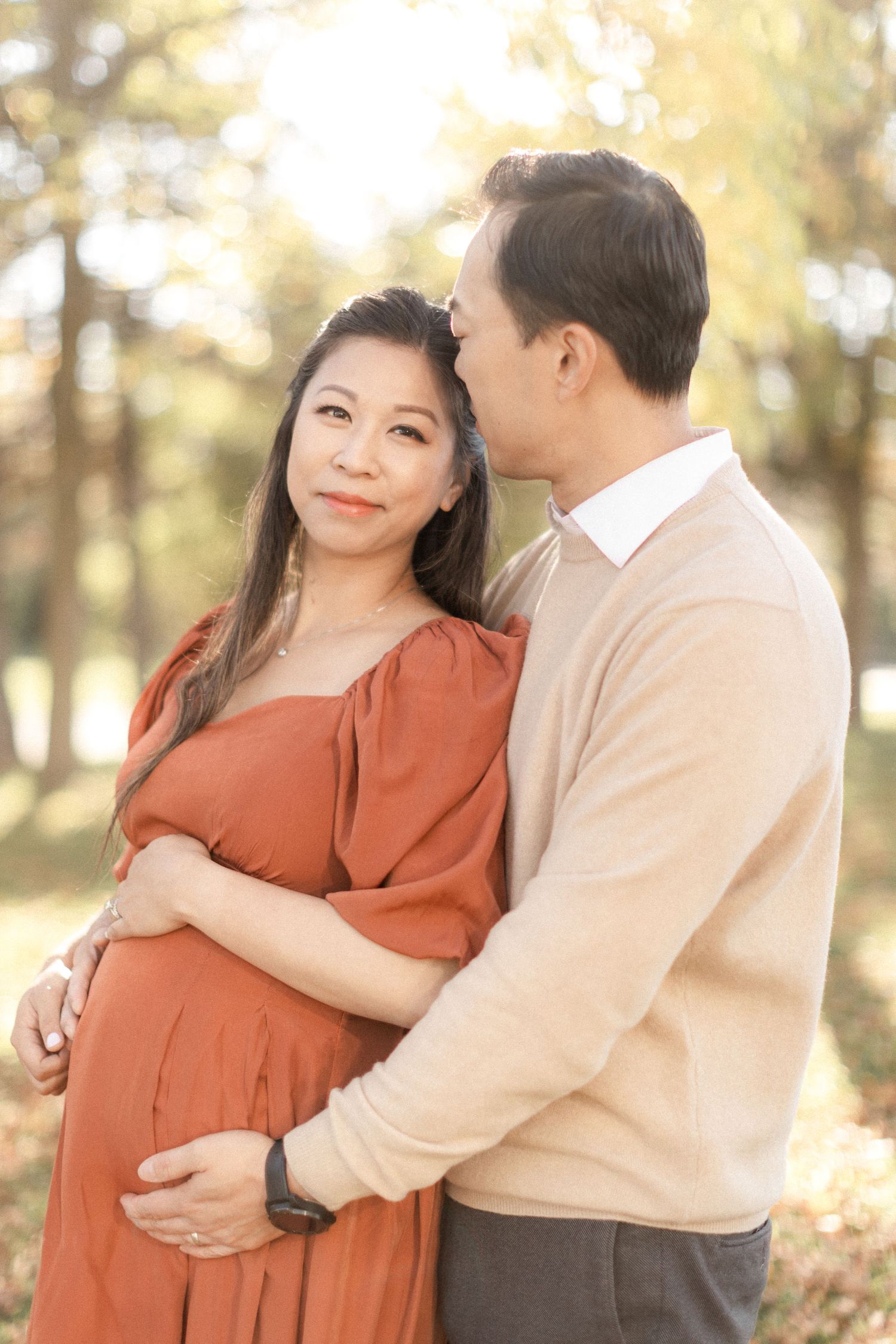 An intimate maternity portrait with soft lighting and earth-toned clothing in an outdoor setting.
