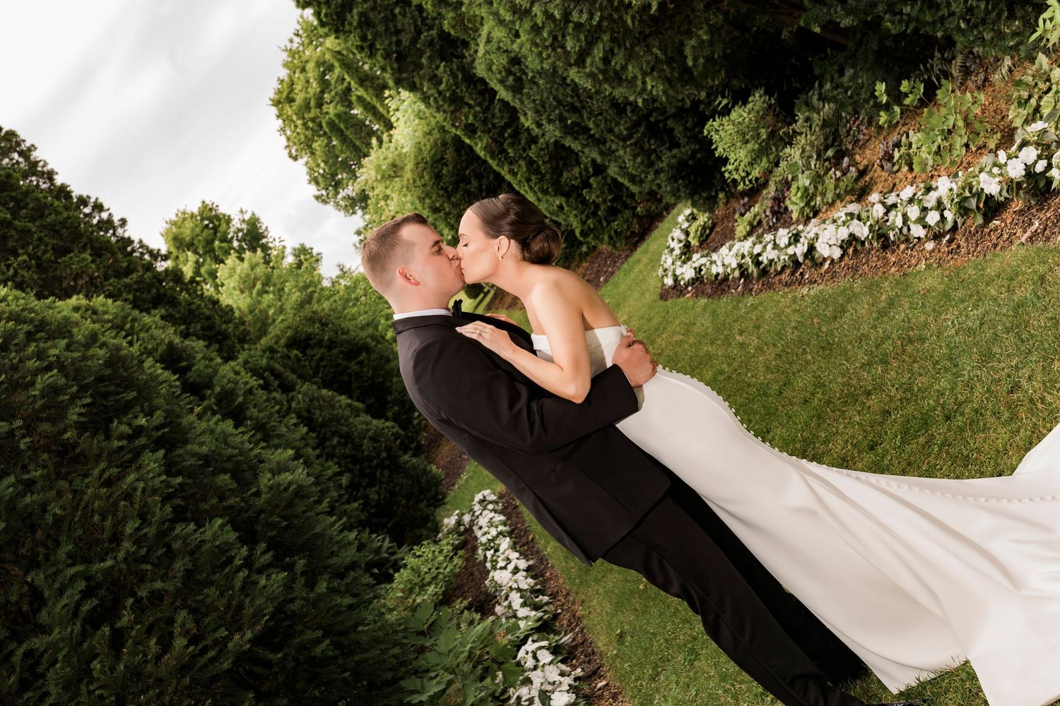 Wedding party having fun posing together on a grassy lawn during outdoor summer celebration.