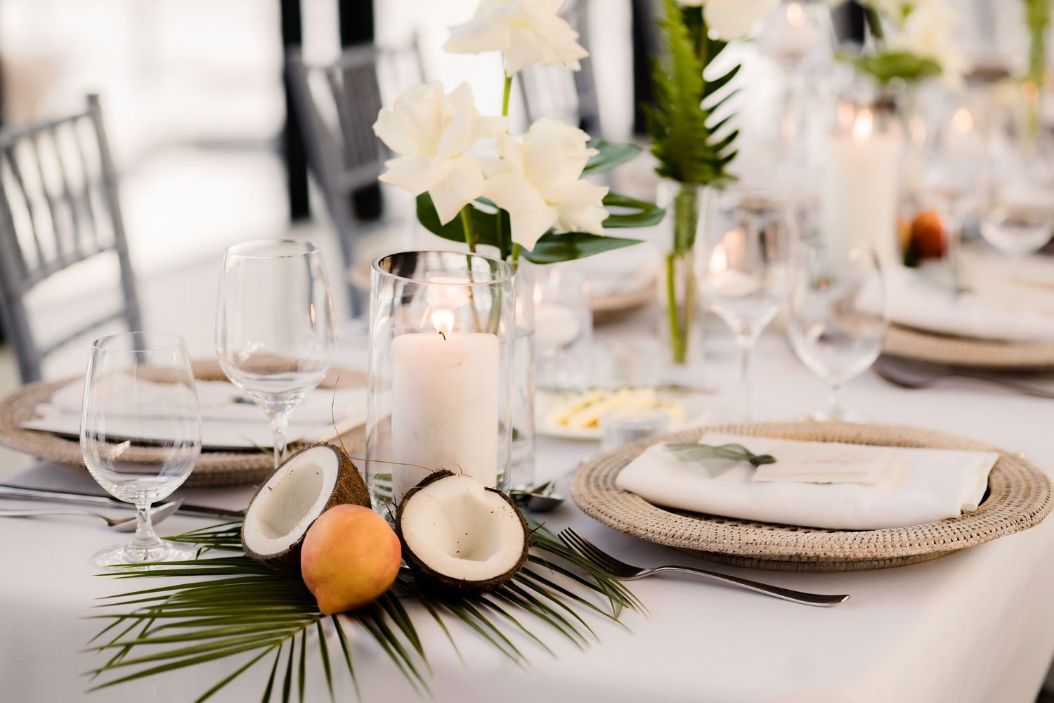 Wedding reception table with tropical decor featuring citrus fruits and white floral arrangements.