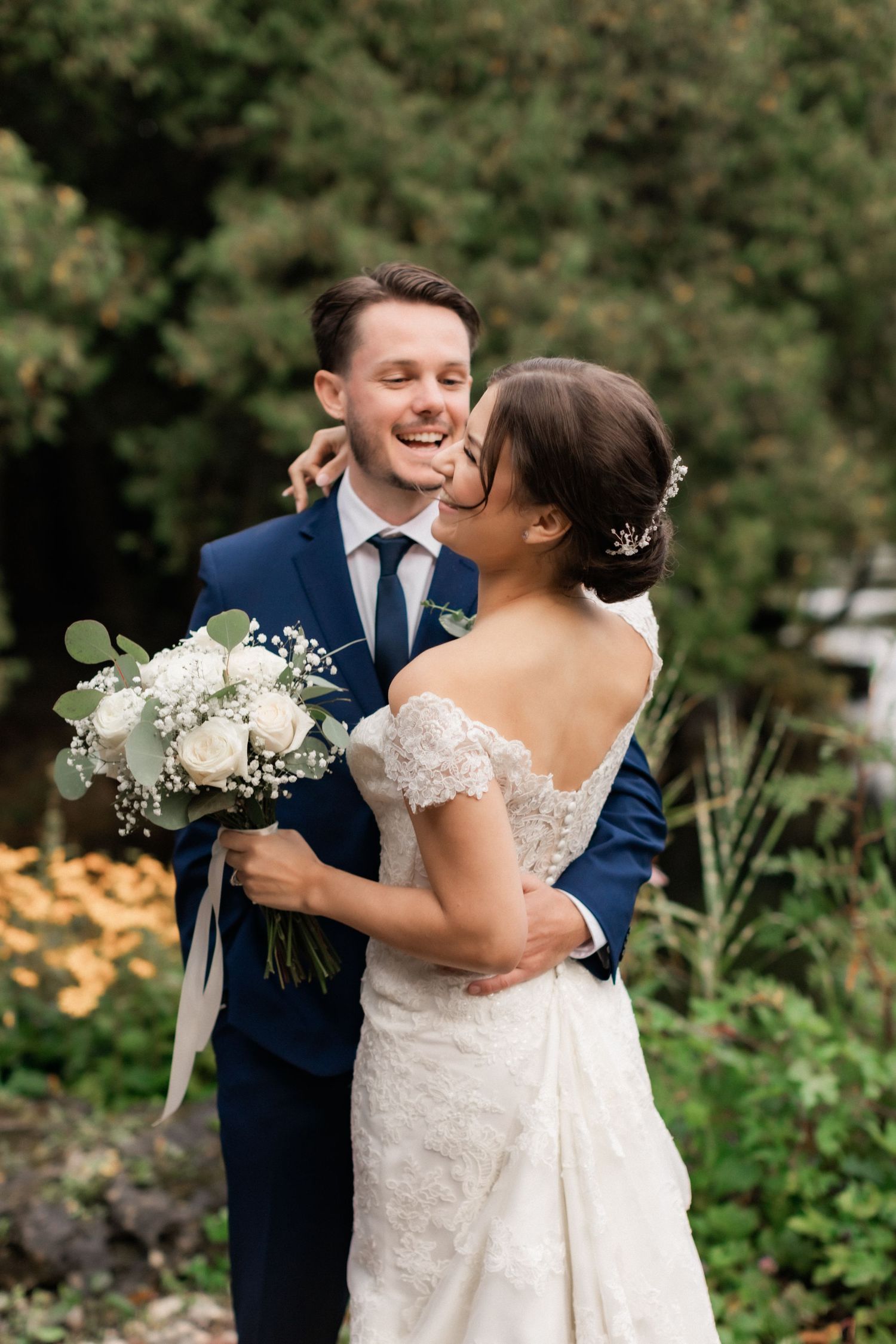 Candid wedding moment shared in garden with white floral bouquet.