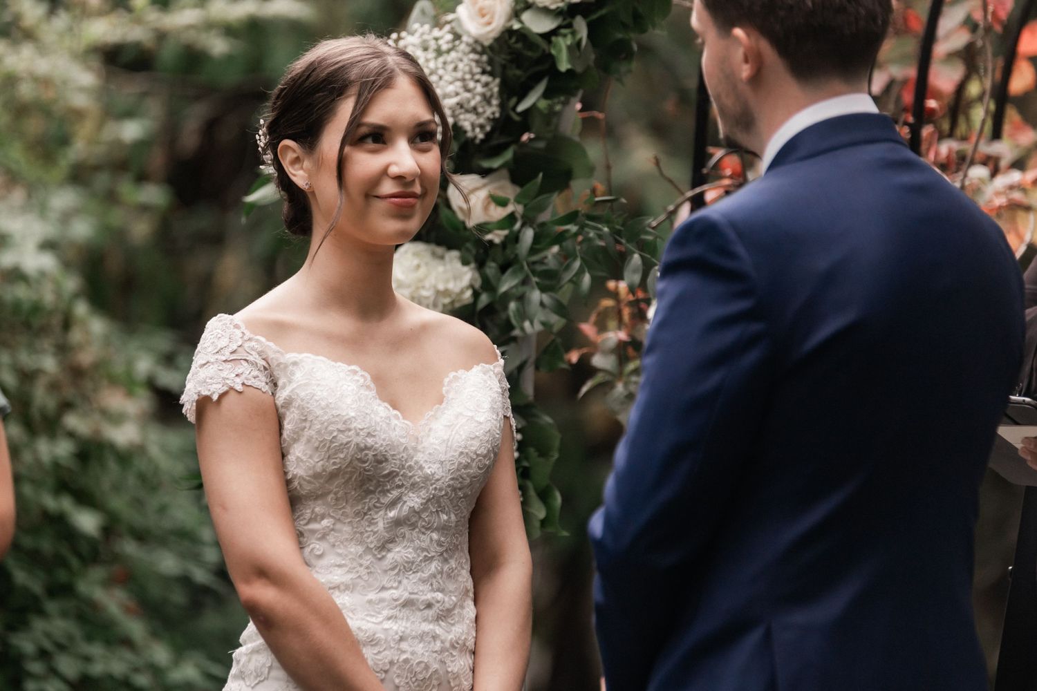 A tender moment during an outdoor wedding ceremony with white floral decorations.