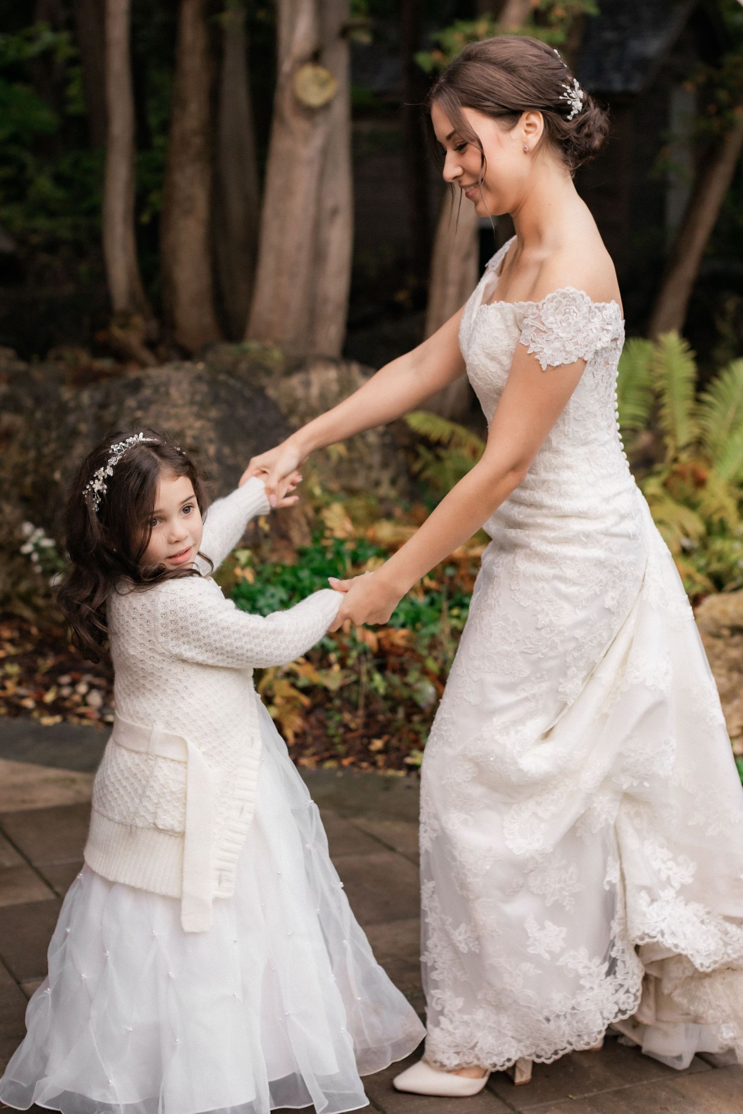 A touching moment between a bride in lace and a young girl in white at a wedding.