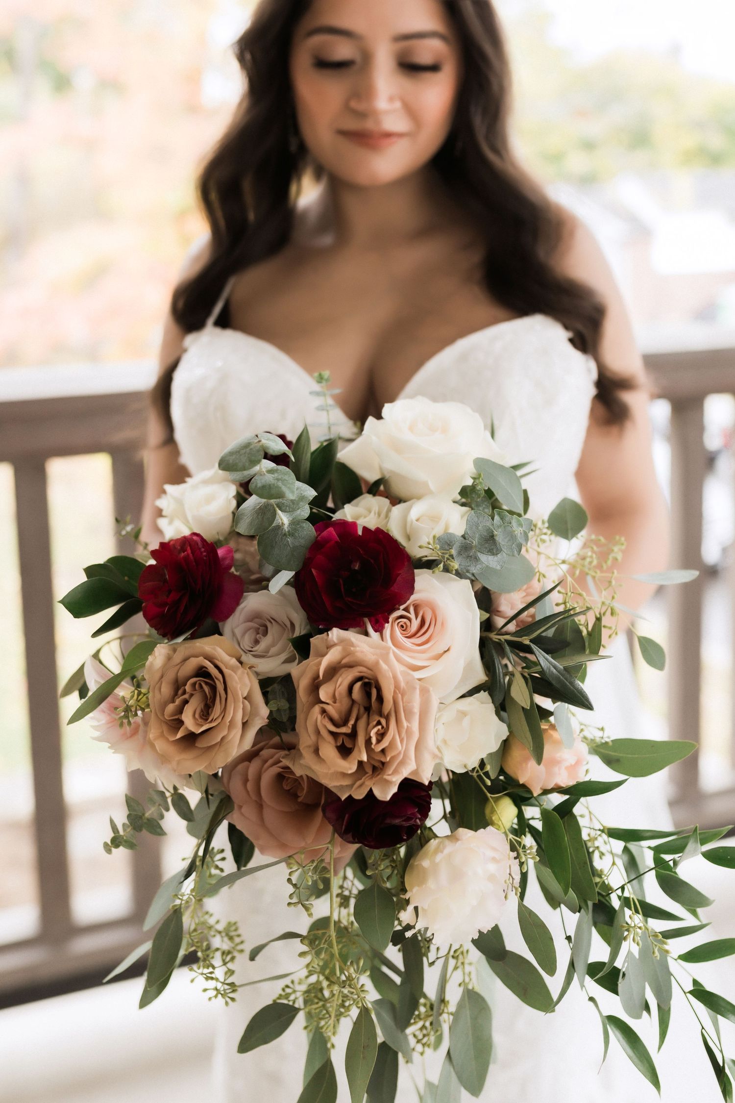 Romantic wedding bouquet with burgundy and champagne roses paired with cascading greenery.