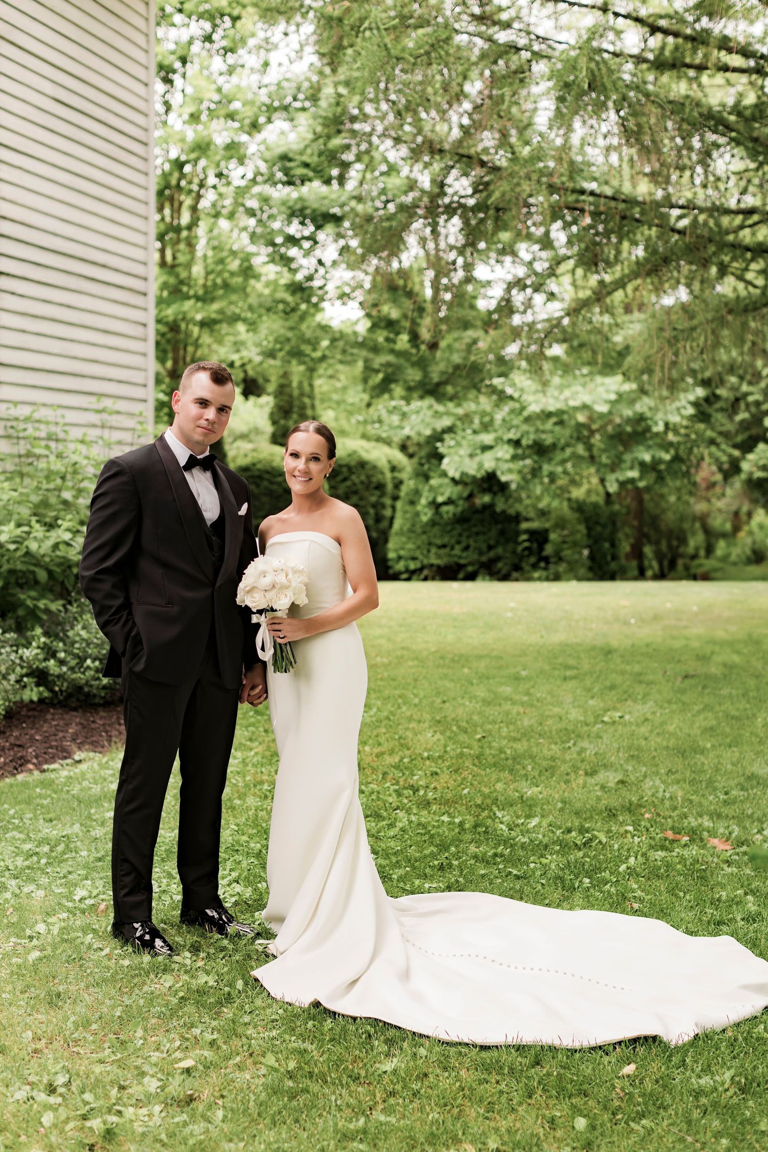 An intimate wedding photo session on a lawn with a dramatic train on the bride's dress.