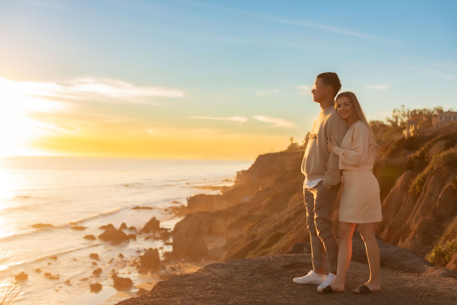 Couple enjoying peaceful sunset moment on California coastal cliffs.