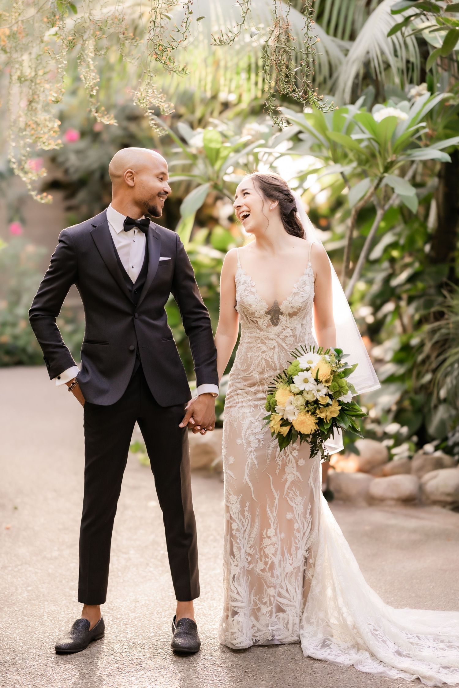 A couple shares an animated laugh together during their wedding photoshoot in a garden.