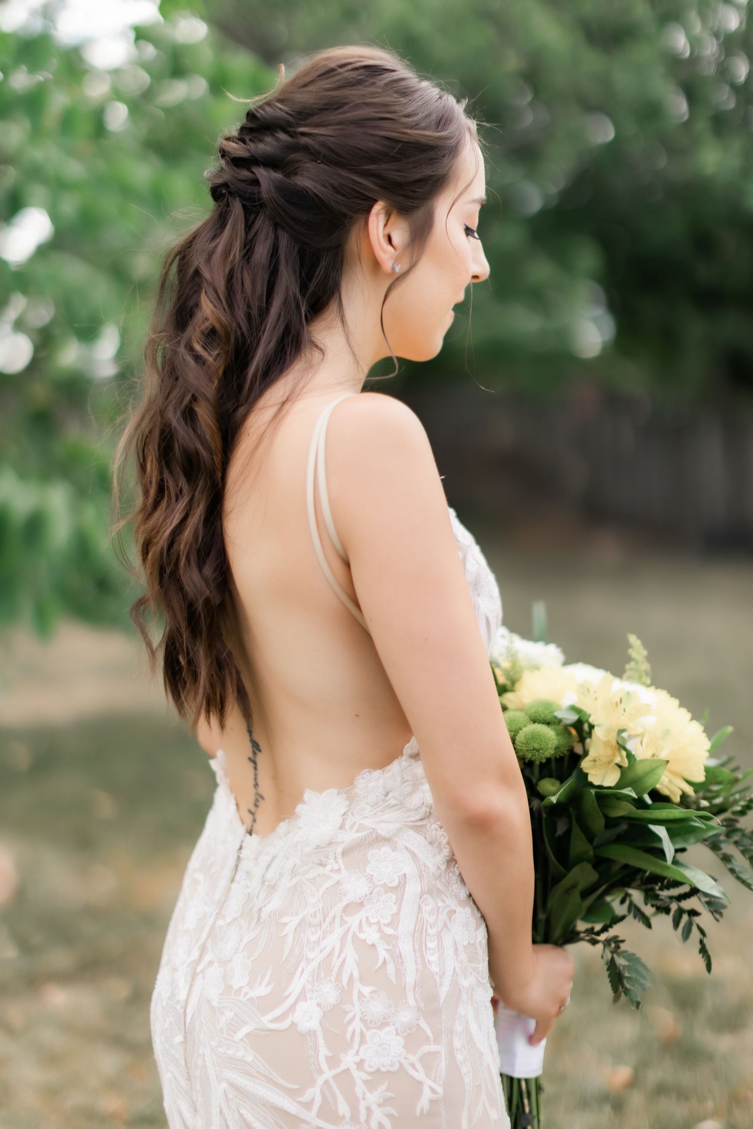 Back view of an intricate braided hairstyle and open-back lace wedding dress.