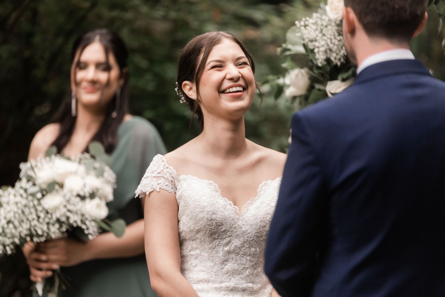 Joyful moment captured during outdoor wedding ceremony with bridesmaid holding baby's breath bouquet.