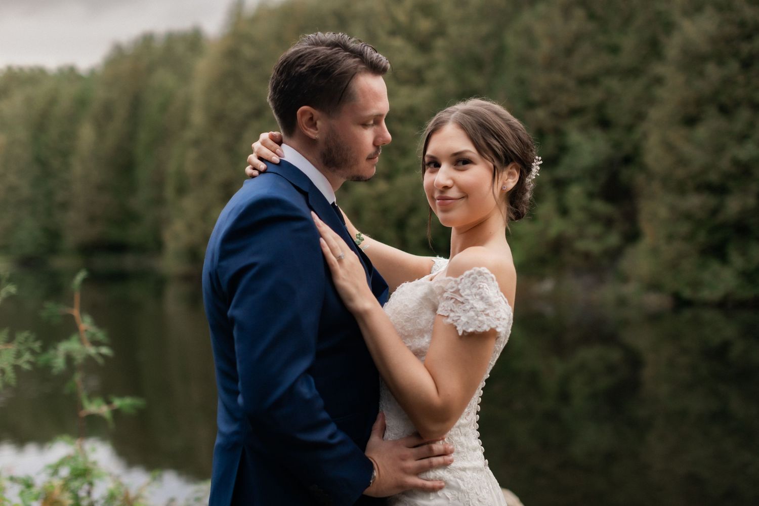 A romantic wedding portrait captured against a serene lake backdrop.