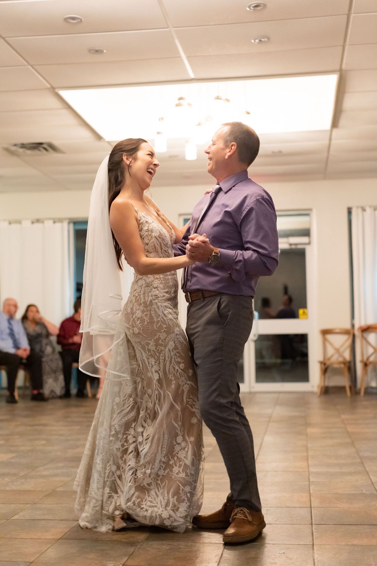 A bride in a lace gown dances with her partner during a heartfelt reception moment.