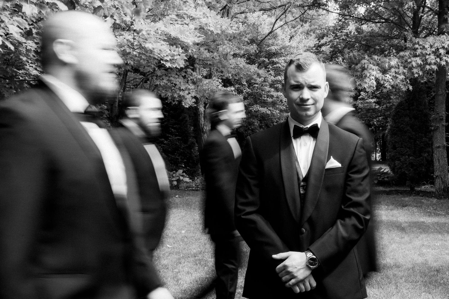 Black and white portrait of groomsmen in formal attire gathered outdoors.