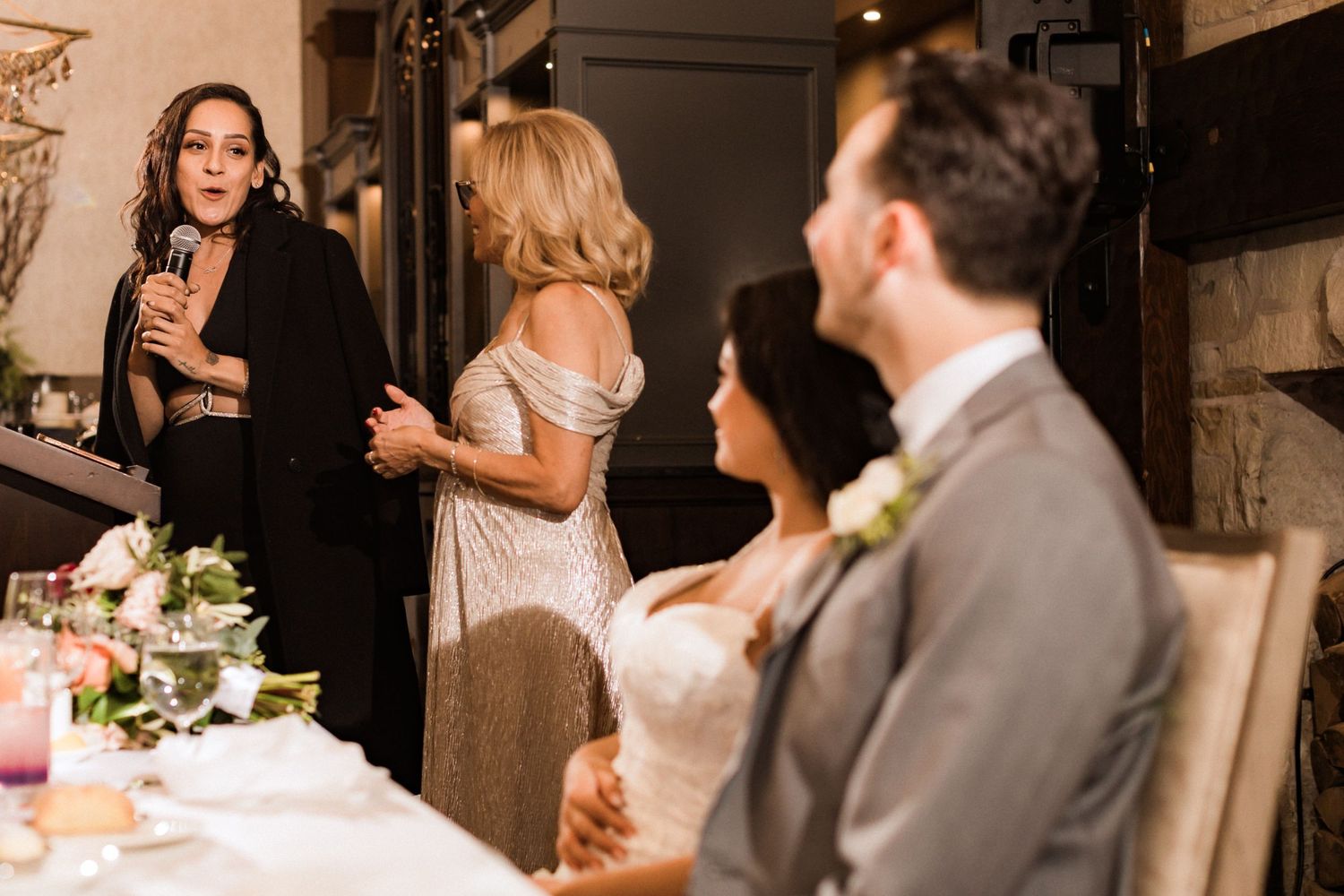 Wedding reception speech delivered as guests listen attentively at elegantly decorated venue.