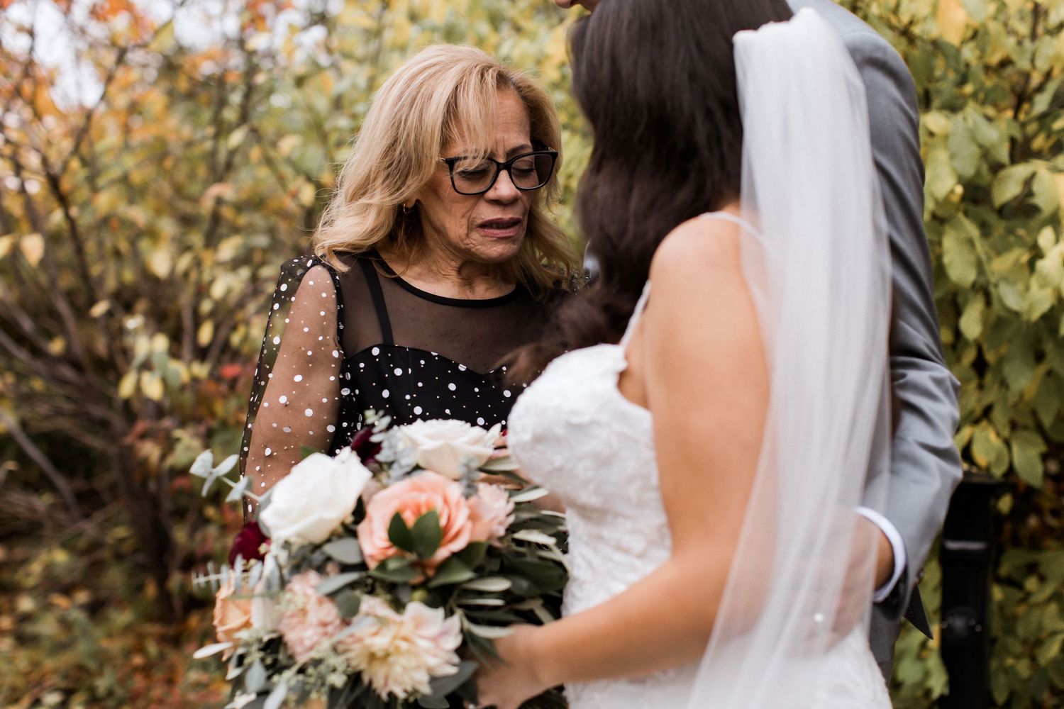 Intimate outdoor wedding moment with autumn foliage and delicate floral arrangements.