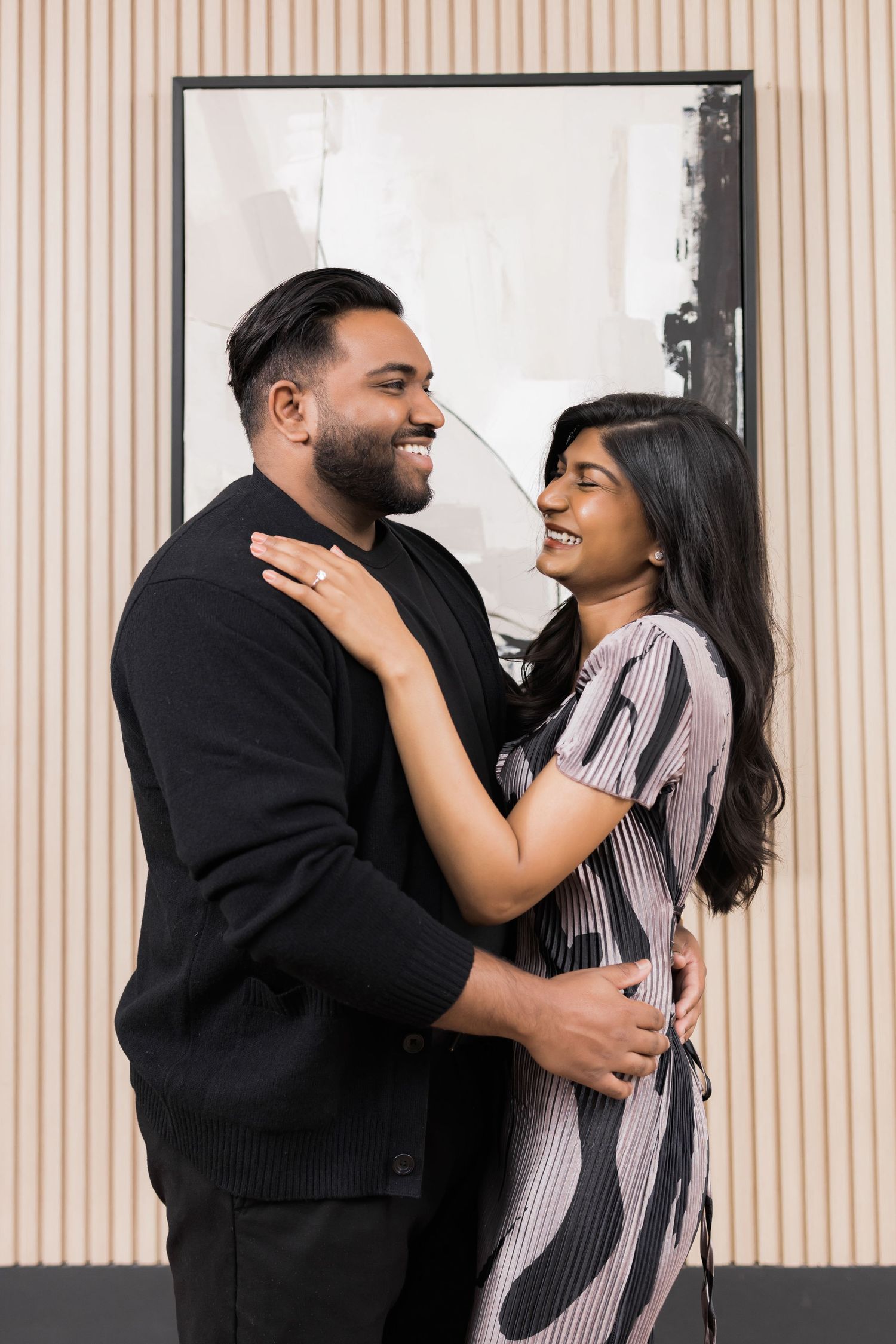 A couple shares an intimate embrace against a modern striped wall backdrop.