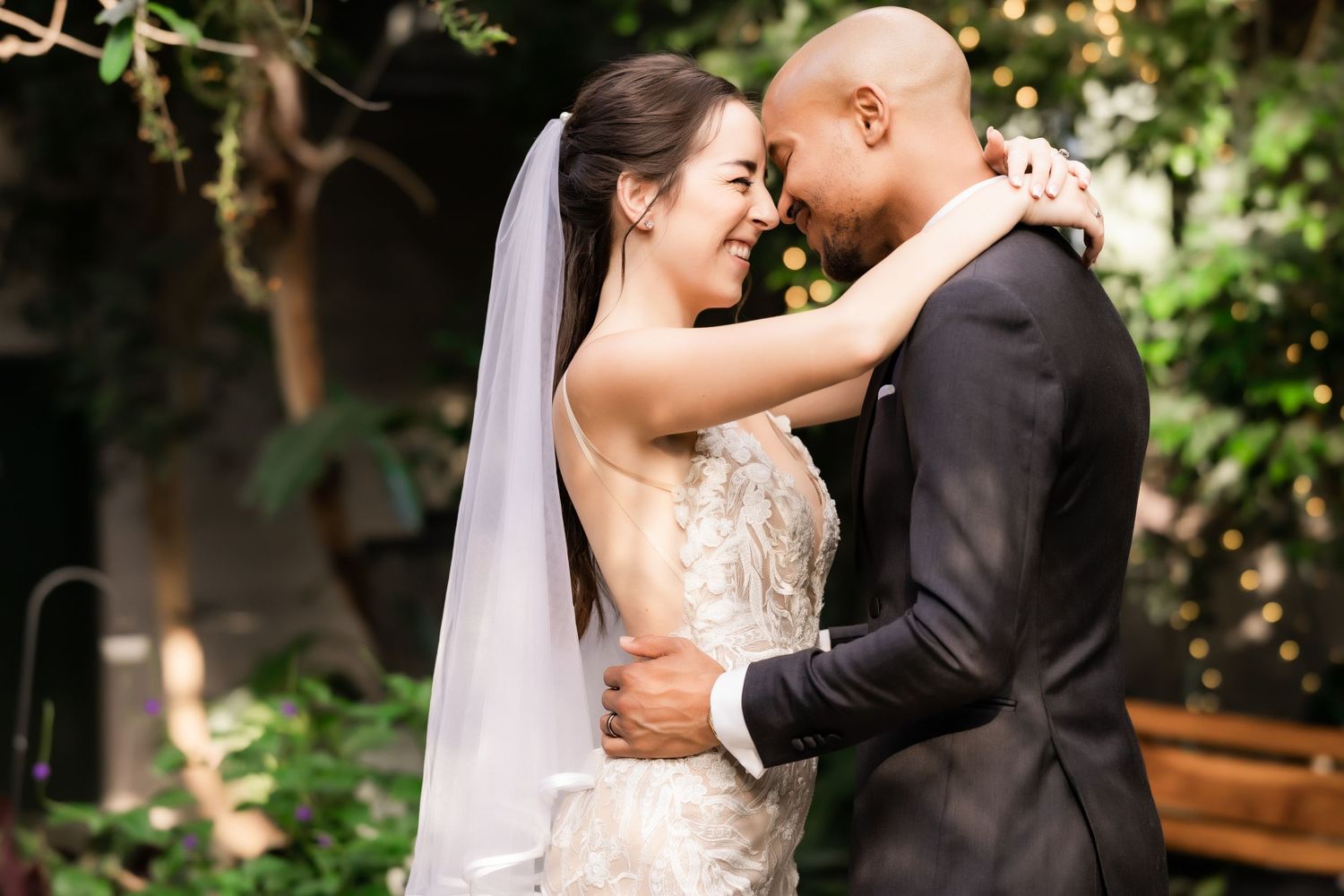 Romantic wedding embrace captured in a lush garden setting with natural light.