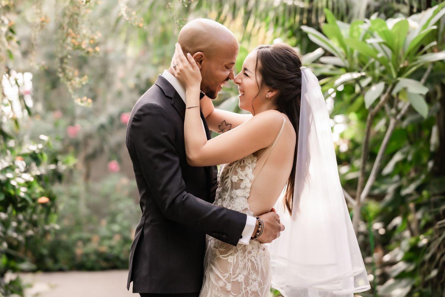 Intimate wedding portrait showing tender embrace against tropical garden backdrop.
