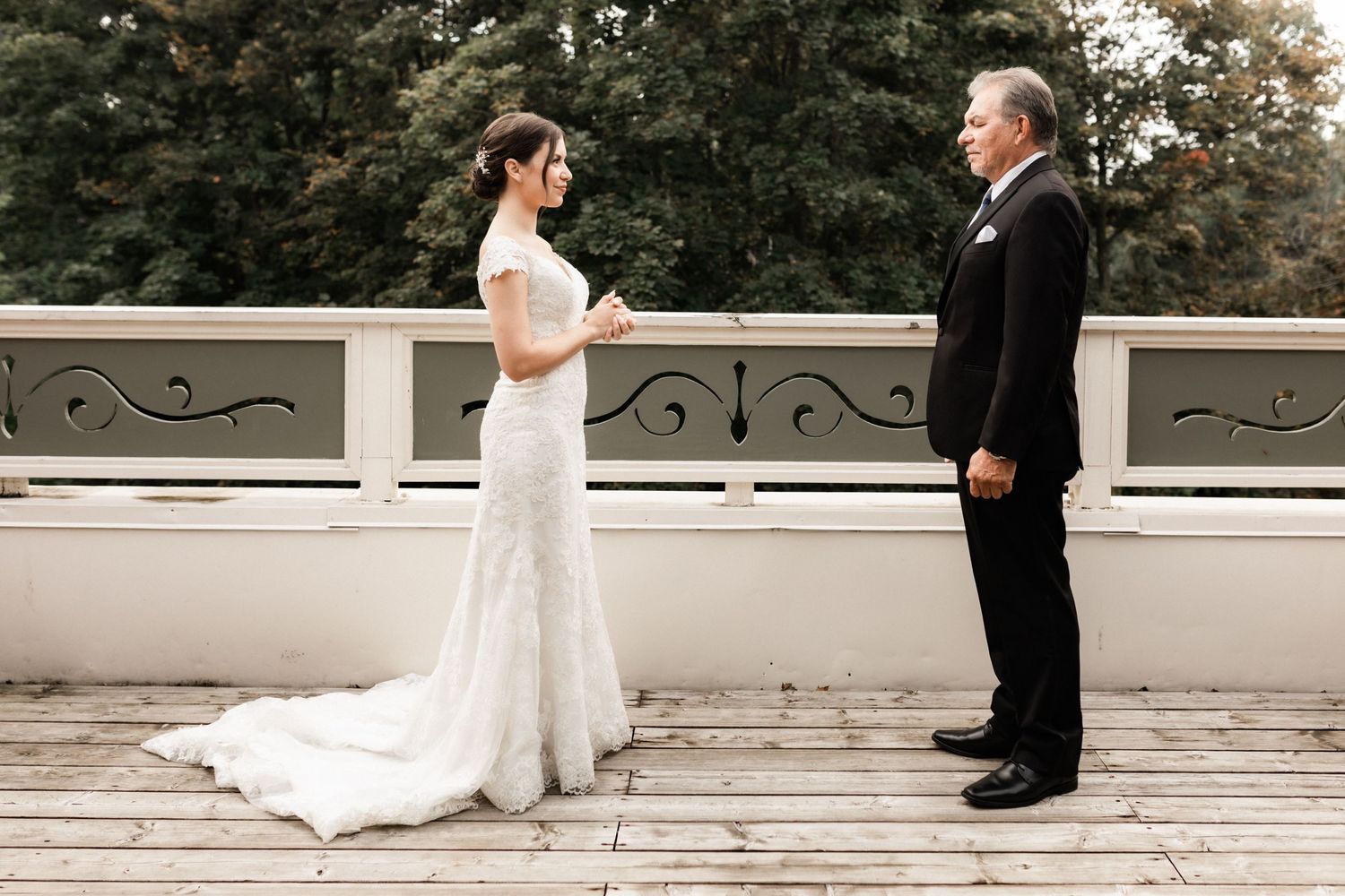 Emotional wedding moment between couple on wooden deck with ornate railing.