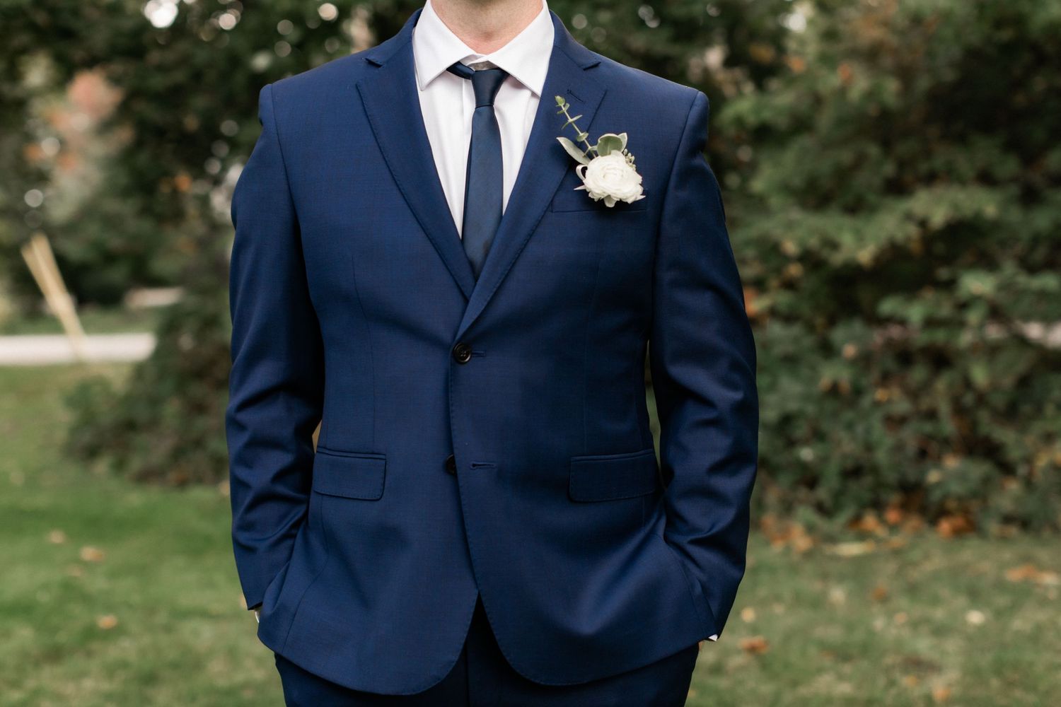 Close-up detail of navy blue wedding suit with white boutonniere.