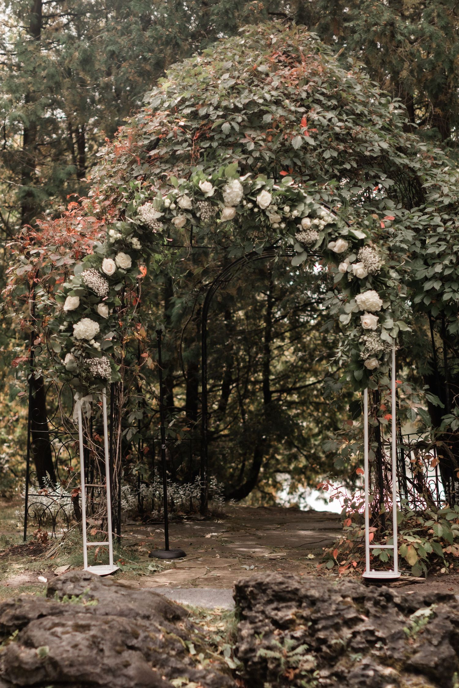 Beautiful garden wedding arch with white roses and greenery creating a romantic entrance.
