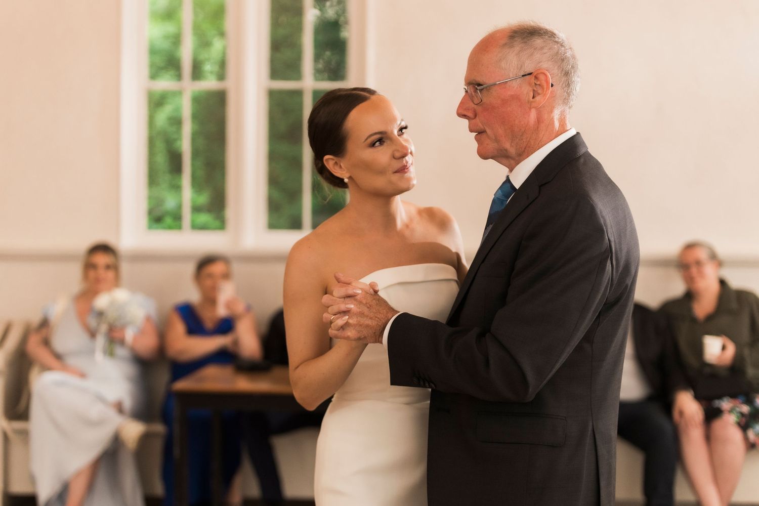 Special dance captured at wedding reception with guests watching in background of bright venue.