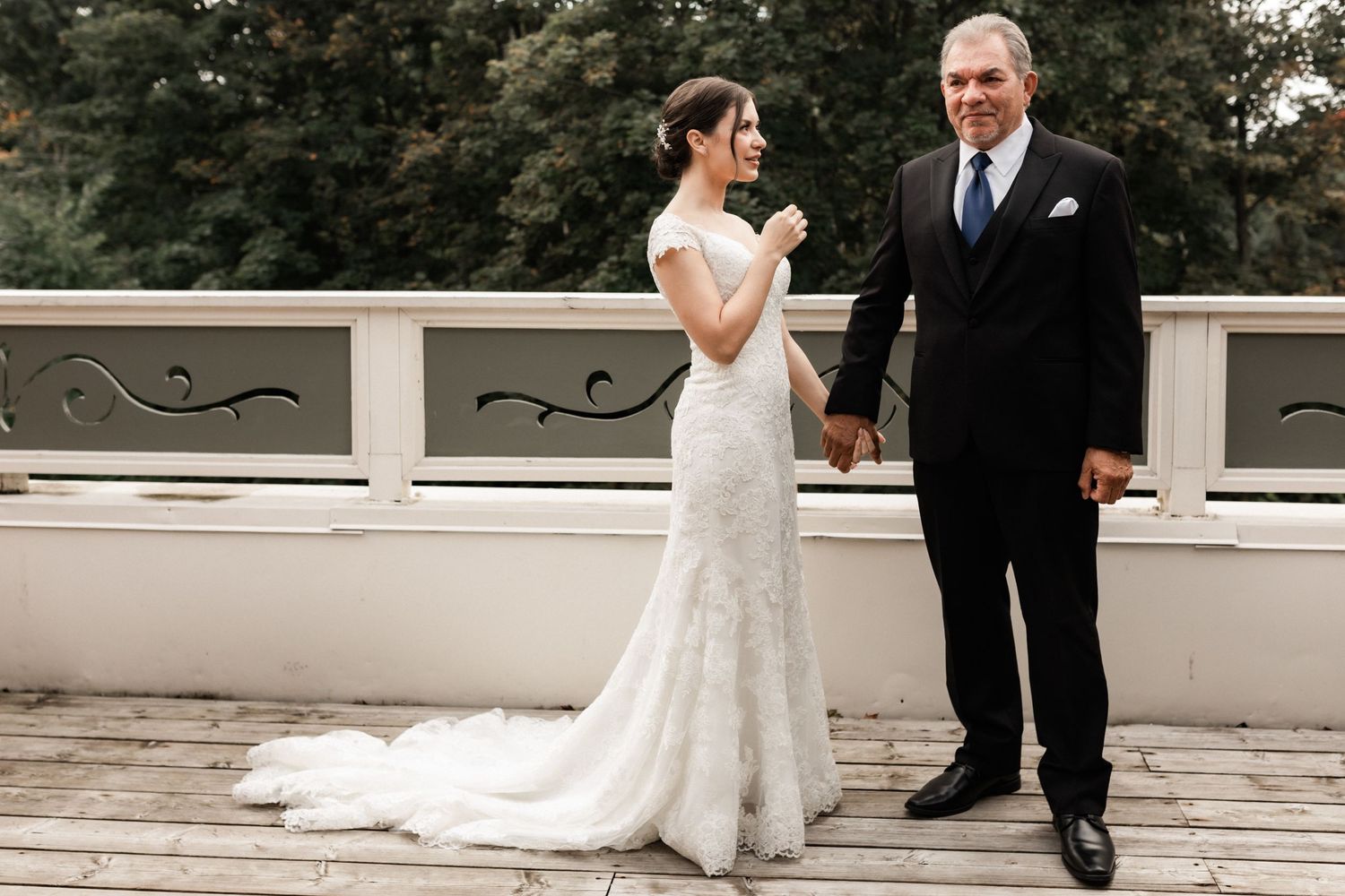 Outdoor wedding portrait on white terrace with ornate railing details.