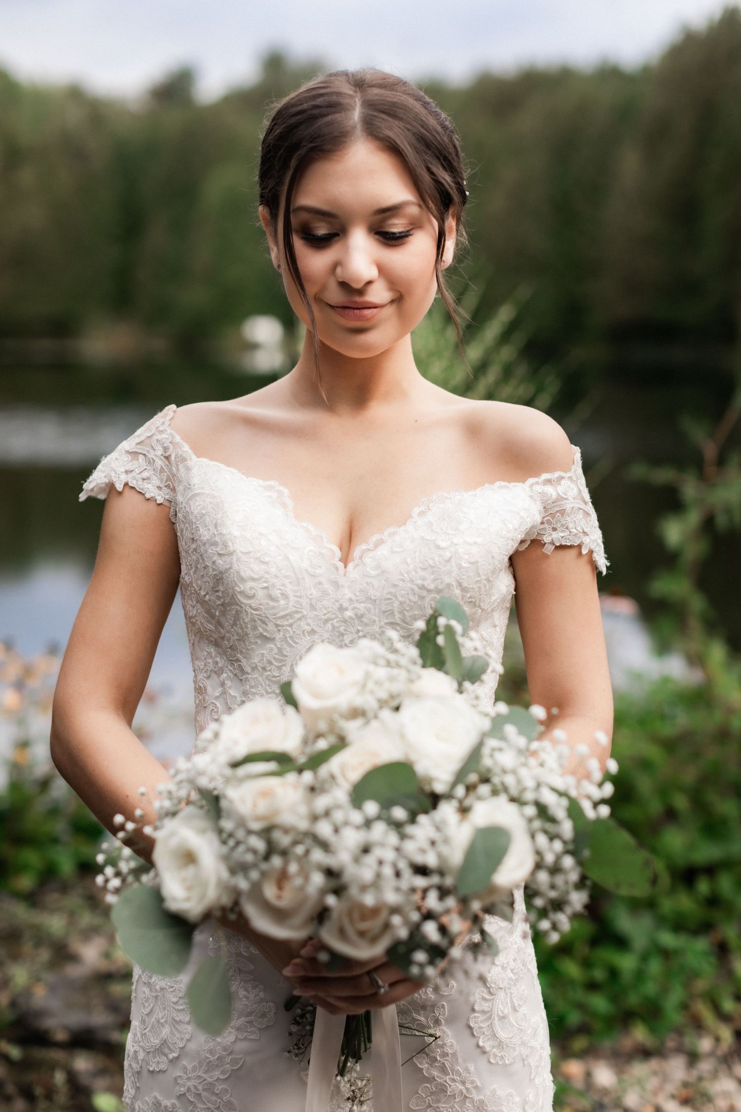 A close-up bridal portrait showcasing a delicate lace dress and white rose bouquet.