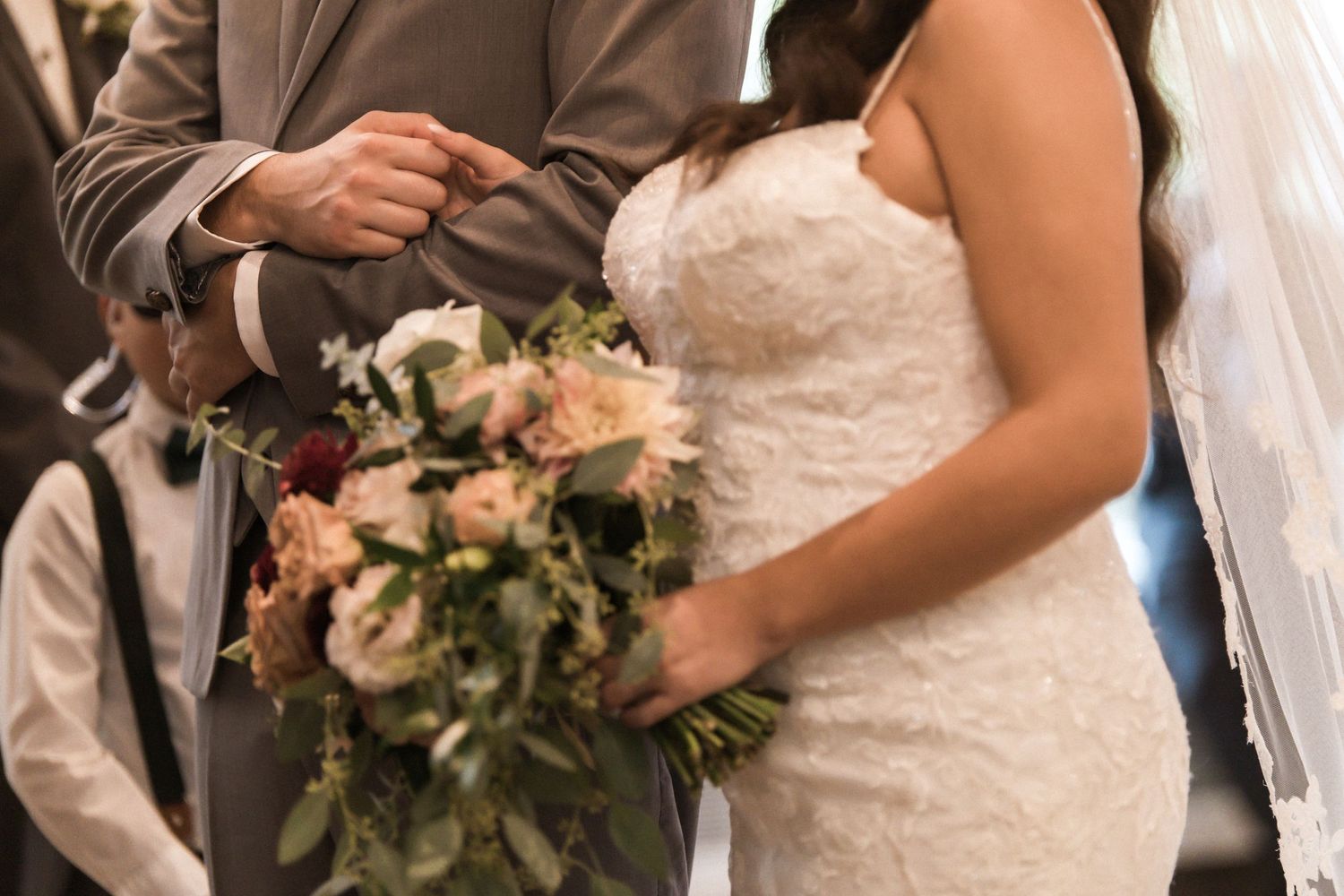 Close-up of a bridal bouquet with blush pink roses and greenery during the wedding ceremony.