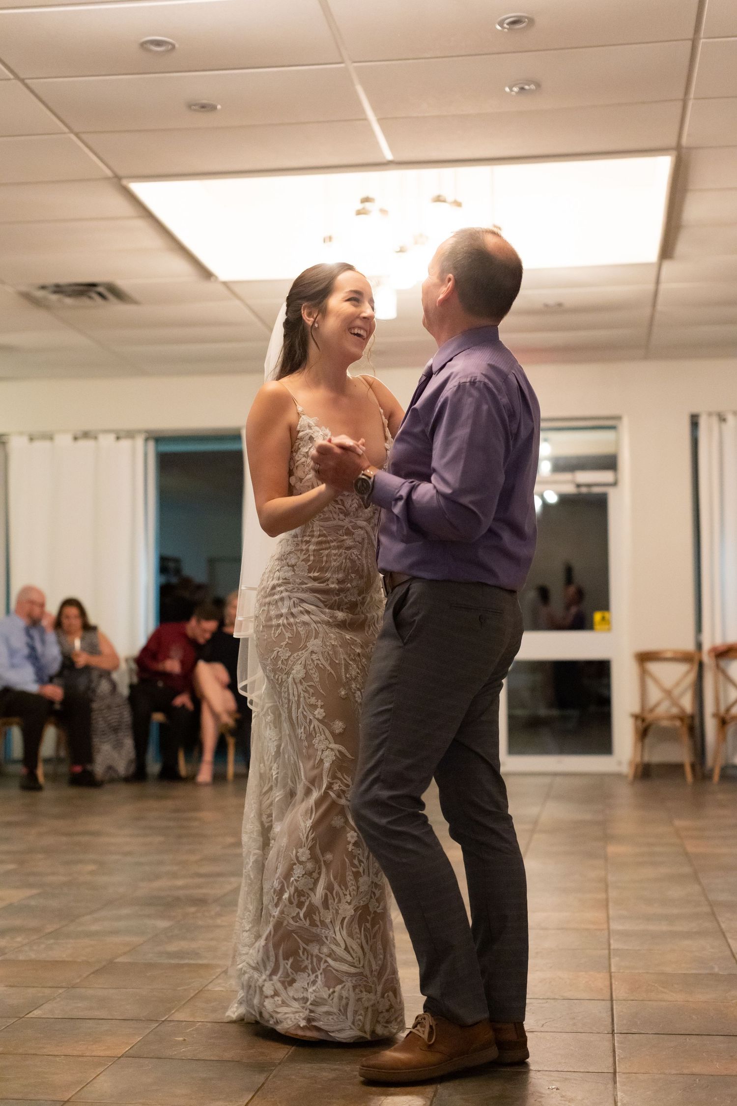 A couple shares their first dance in an elegantly decorated reception hall with tiled floors.
