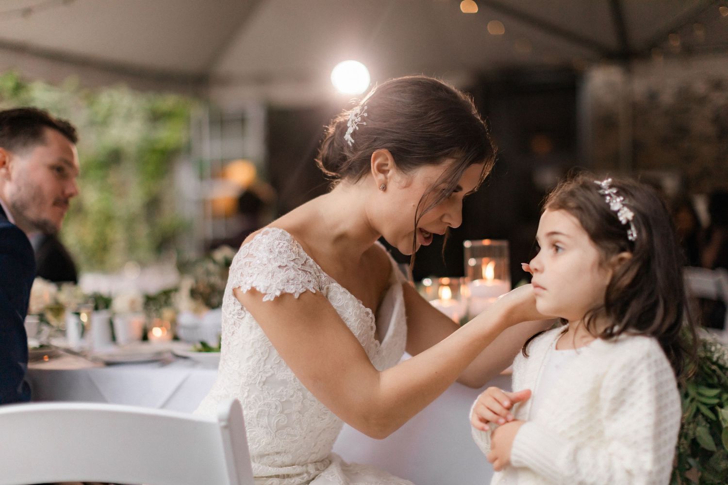 A sweet reception moment between a bride and young girl during the wedding celebration.